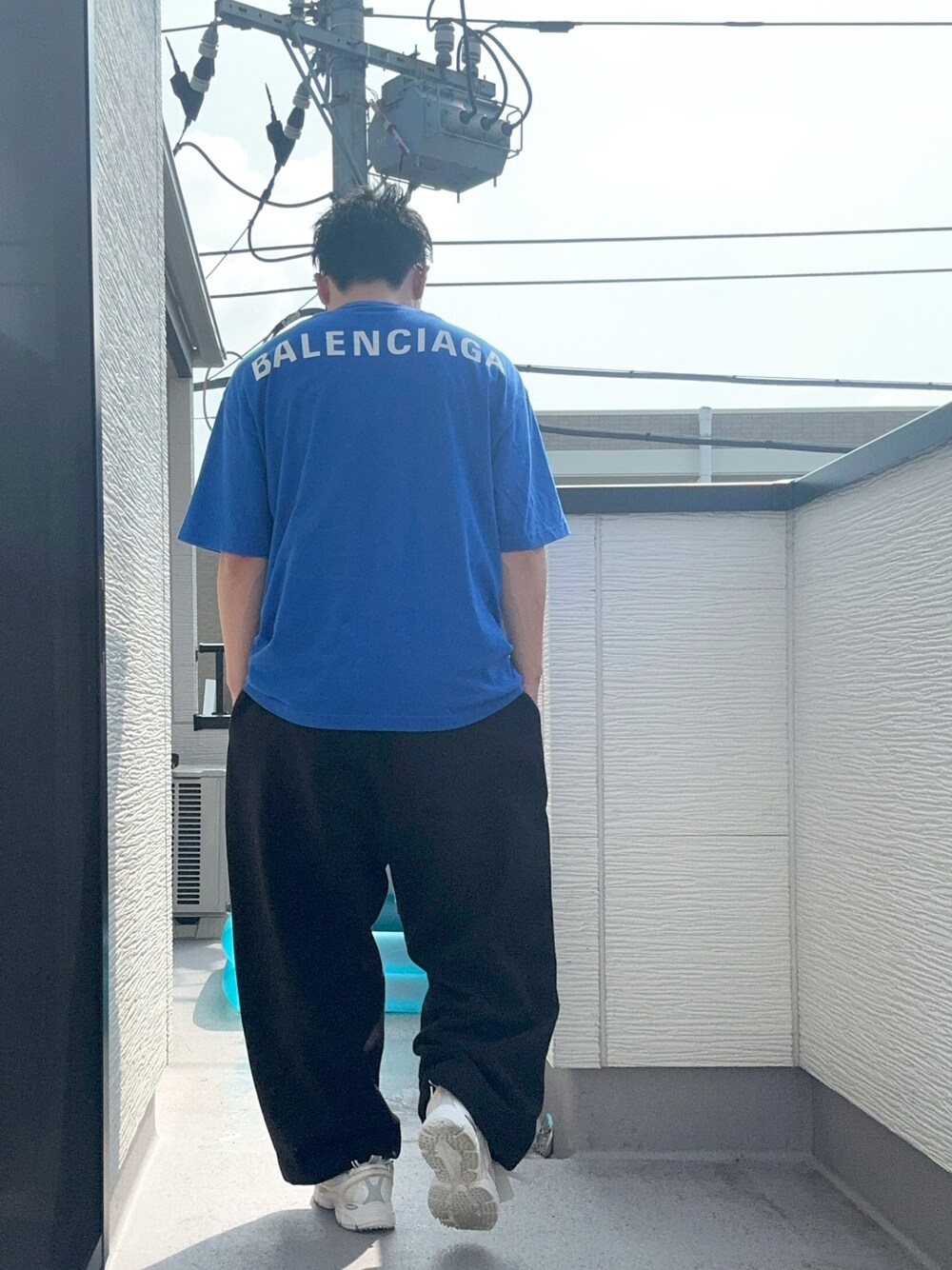 ブラック系のスウェットパンツ、ブルー系のTシャツ/カットソー、ホワイト系のスニーカーを着用したメンズの夏コーディネートの1枚目の写真