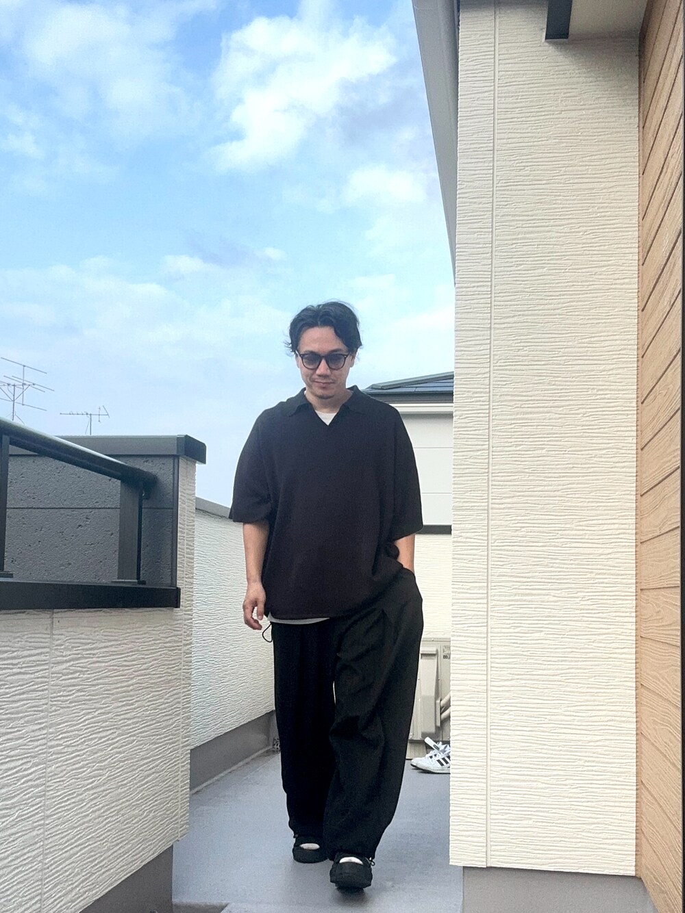 ブラック系のポロシャツ、ブラック系のスウェットパンツ、ブラック系のサンダルを着用したメンズの夏コーディネートの1枚目の写真