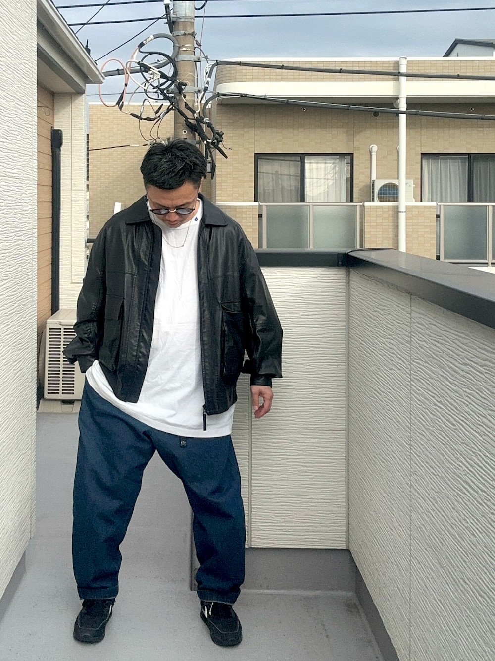 ブルー系のデニムパンツ、ブラック系のブルゾン、ホワイト系のトップスを着用したメンズの秋コーディネートの1枚目の写真