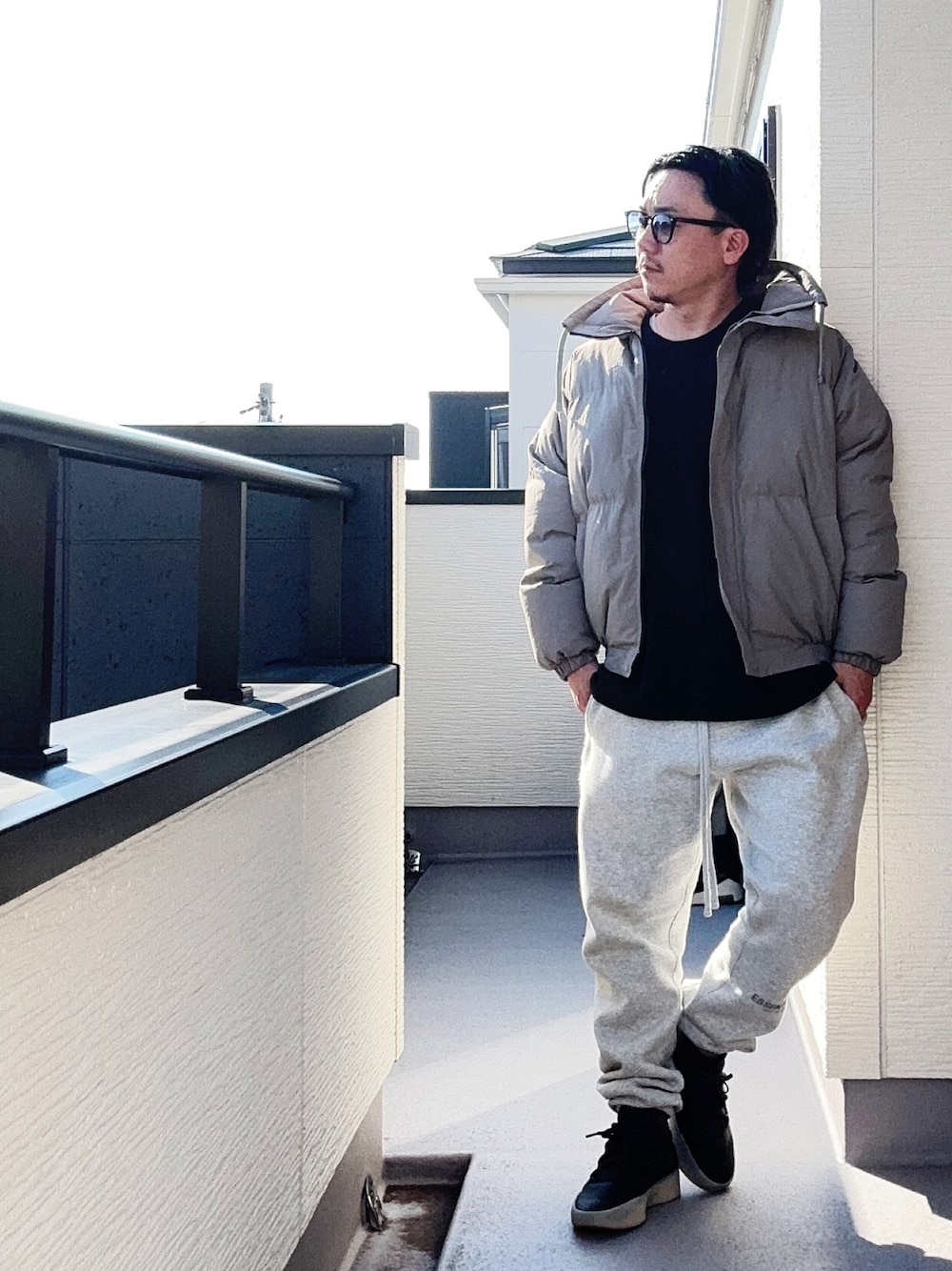 ブラック系のTシャツ/カットソー、グレー系のダウンジャケット/コート、グレー系のスウェットパンツを着用したメンズの秋コーディネートの1枚目の写真