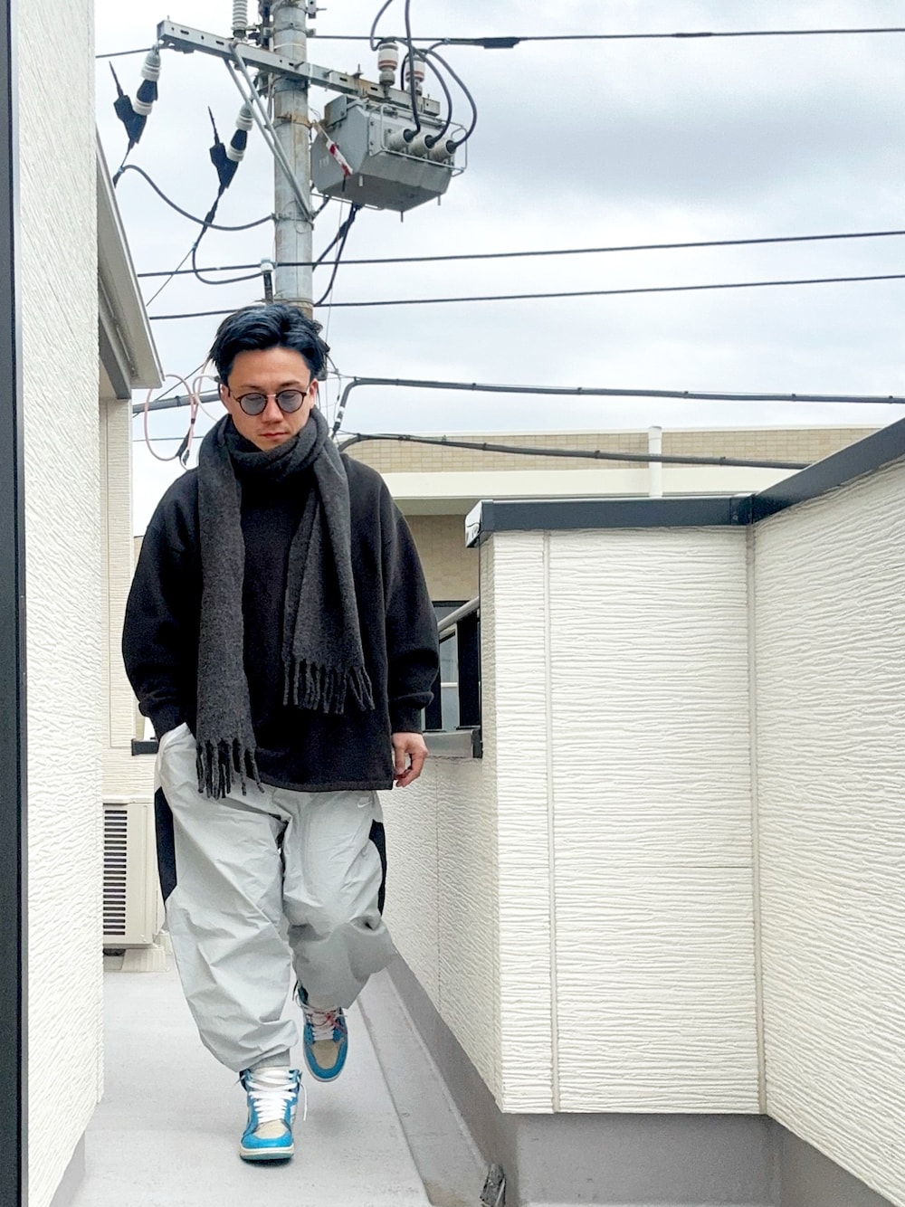 ブラック系のスウェット、グレー系のその他パンツ、ブルー系のスニーカーを着用したメンズの冬コーディネートの1枚目の写真