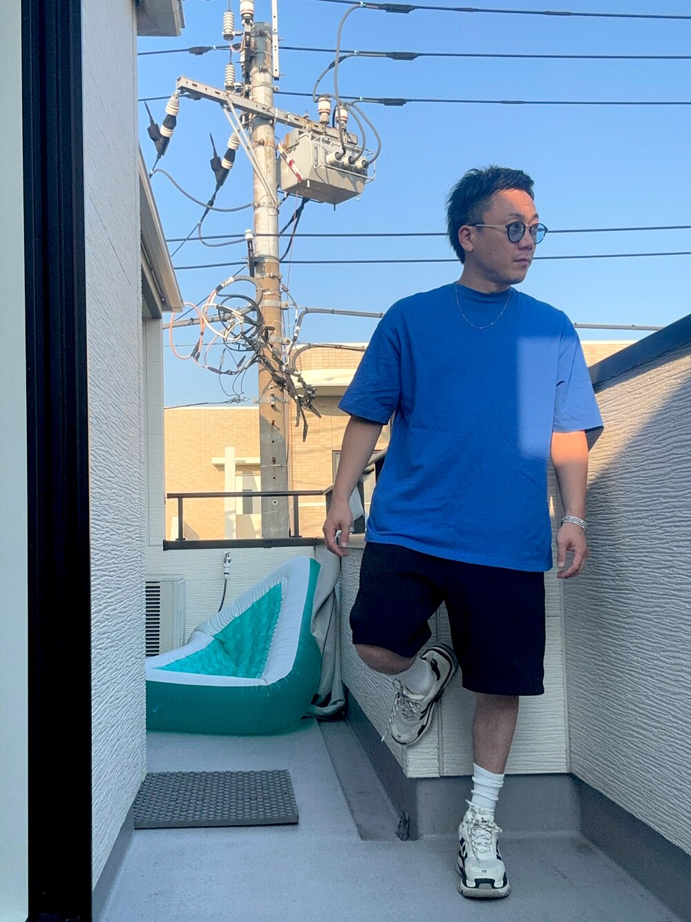 ブルー系のTシャツ/カットソー、ブラック系のスウェットパンツ、ホワイト系のシューズを着用したメンズの秋コーディネートの1枚目の写真