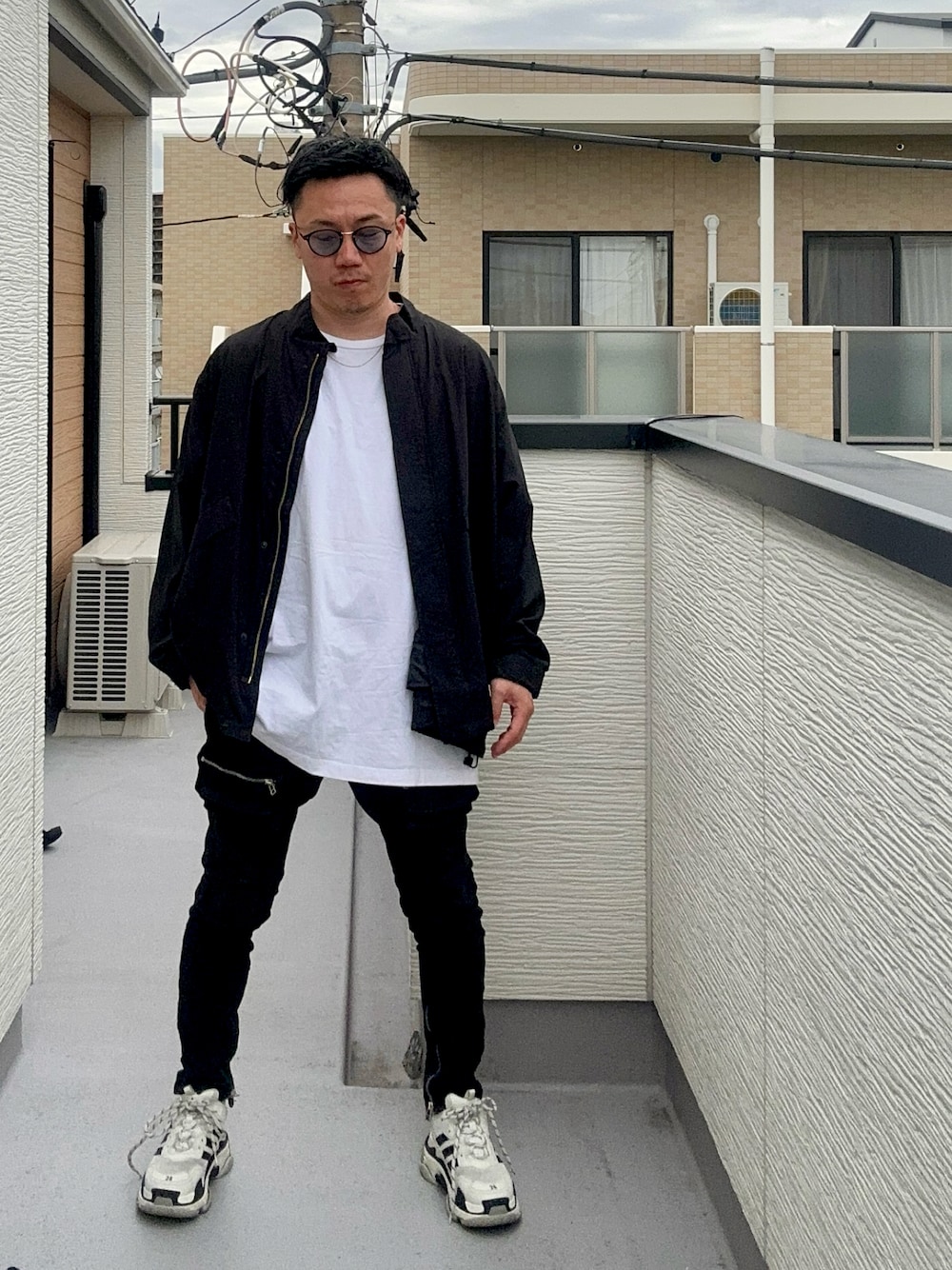 ブラック系のブルゾン、ホワイト系のトップス、ブラック系のデニムパンツを着用したメンズの秋コーディネートの1枚目の写真