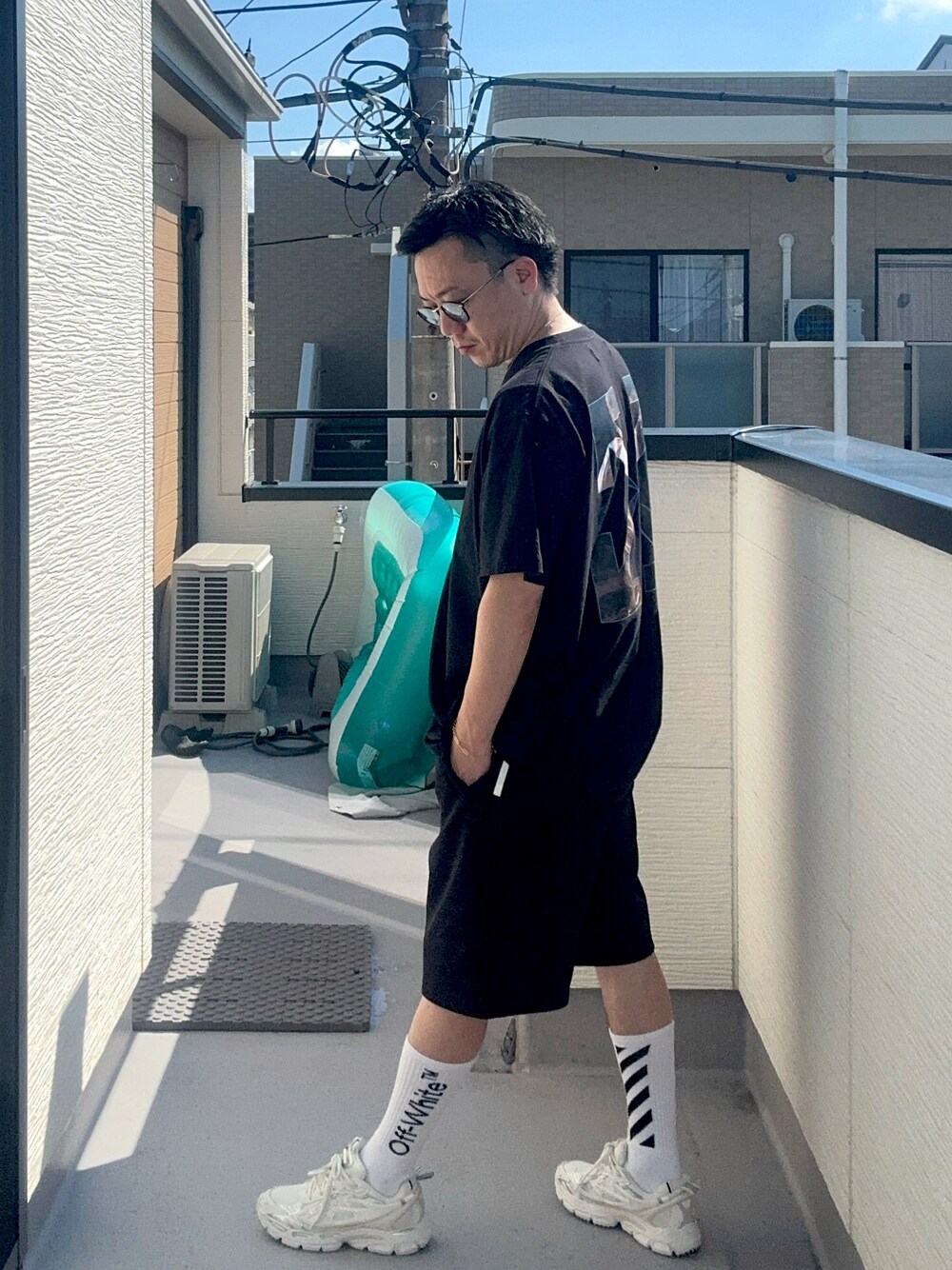 ブラック系のTシャツ/カットソー、ホワイト系のスニーカー、ホワイト系のソックス/靴下を着用したメンズの秋コーディネートの1枚目の写真