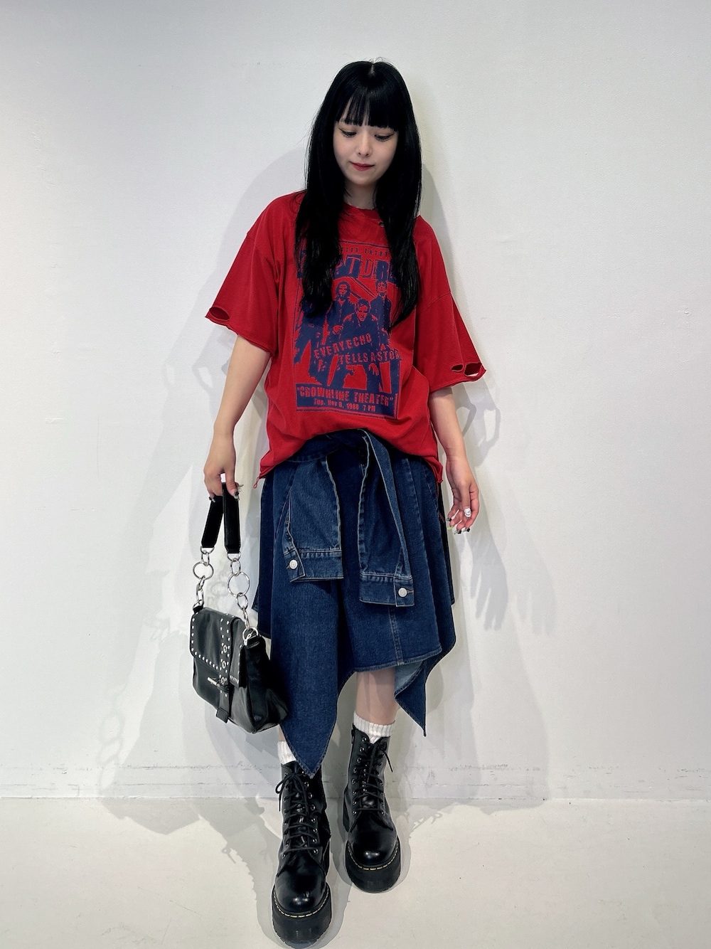 レッド系のTシャツ/カットソー、ブルー系のスカート、ブラック系のブーツを着用したレディースの春コーディネートの1枚目の写真