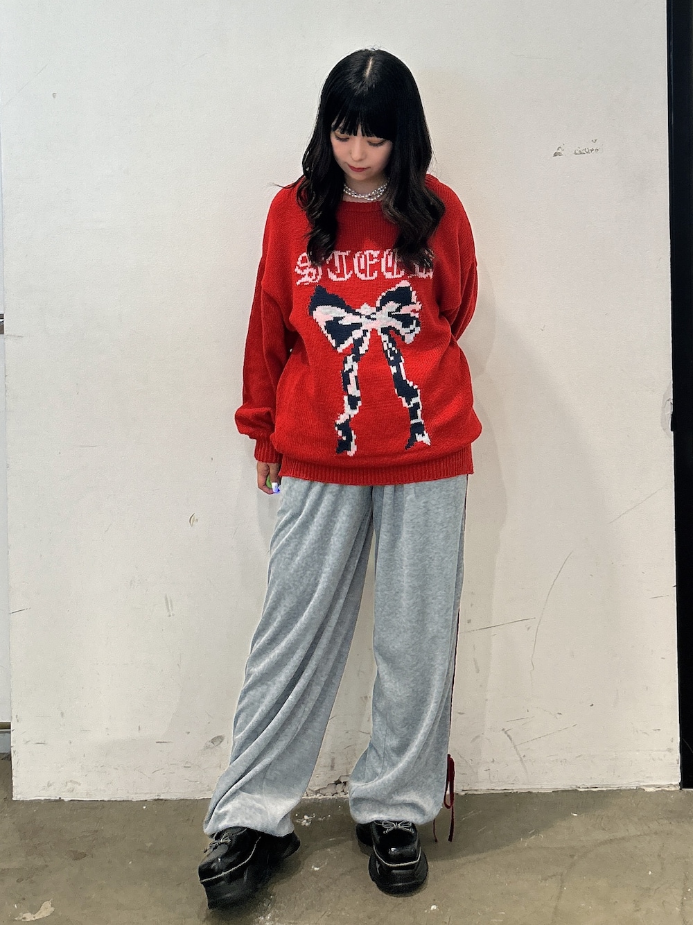 レッド系のニット/セーター、グレー系のその他パンツ、ブラック系のスニーカーを着用したレディースの秋コーディネートの1枚目の写真