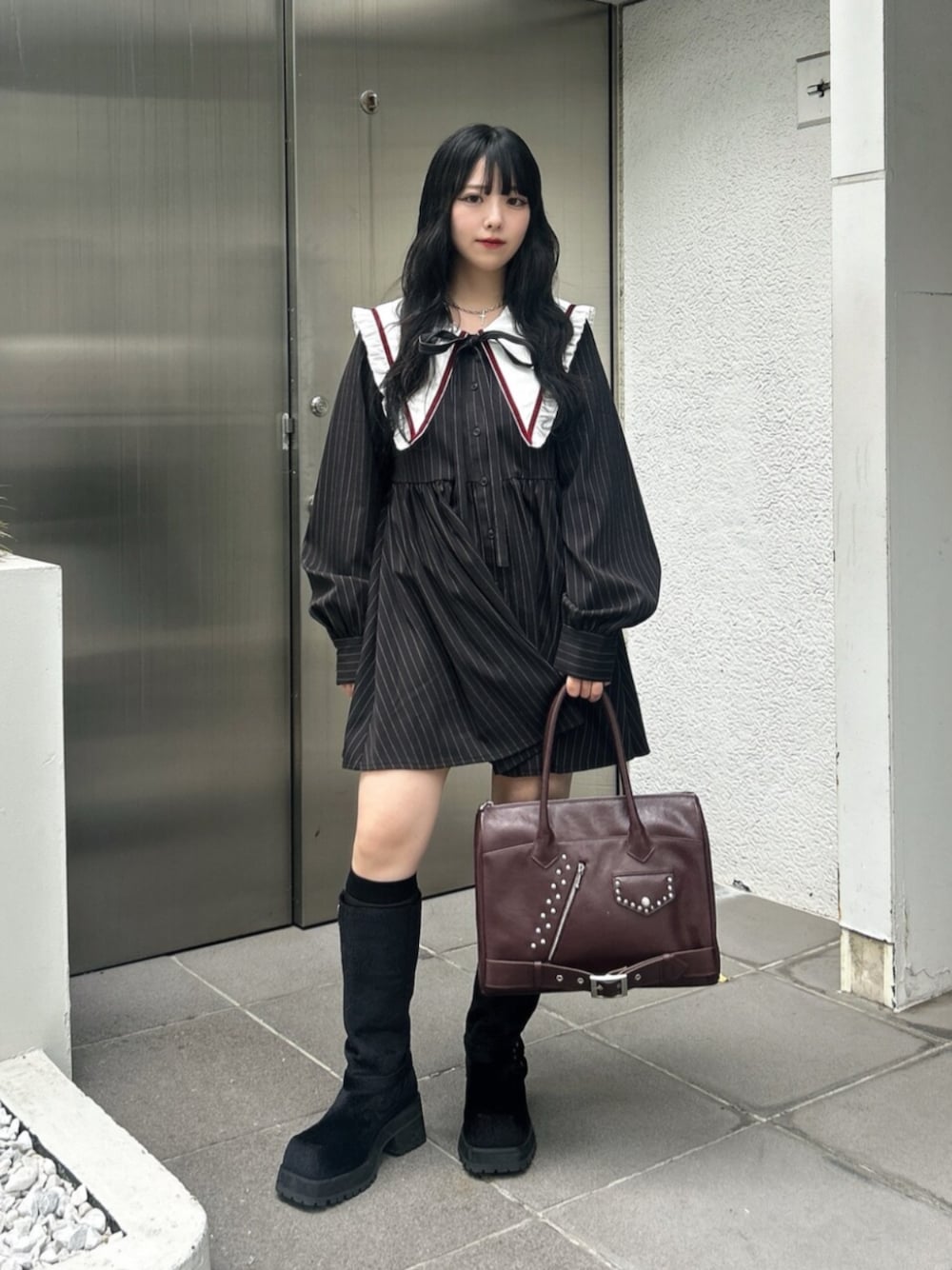 ブラック系のブーツ、ブラック系のワンピース、レッド系のハンドバッグを着用したレディースの秋コーディネートの1枚目の写真