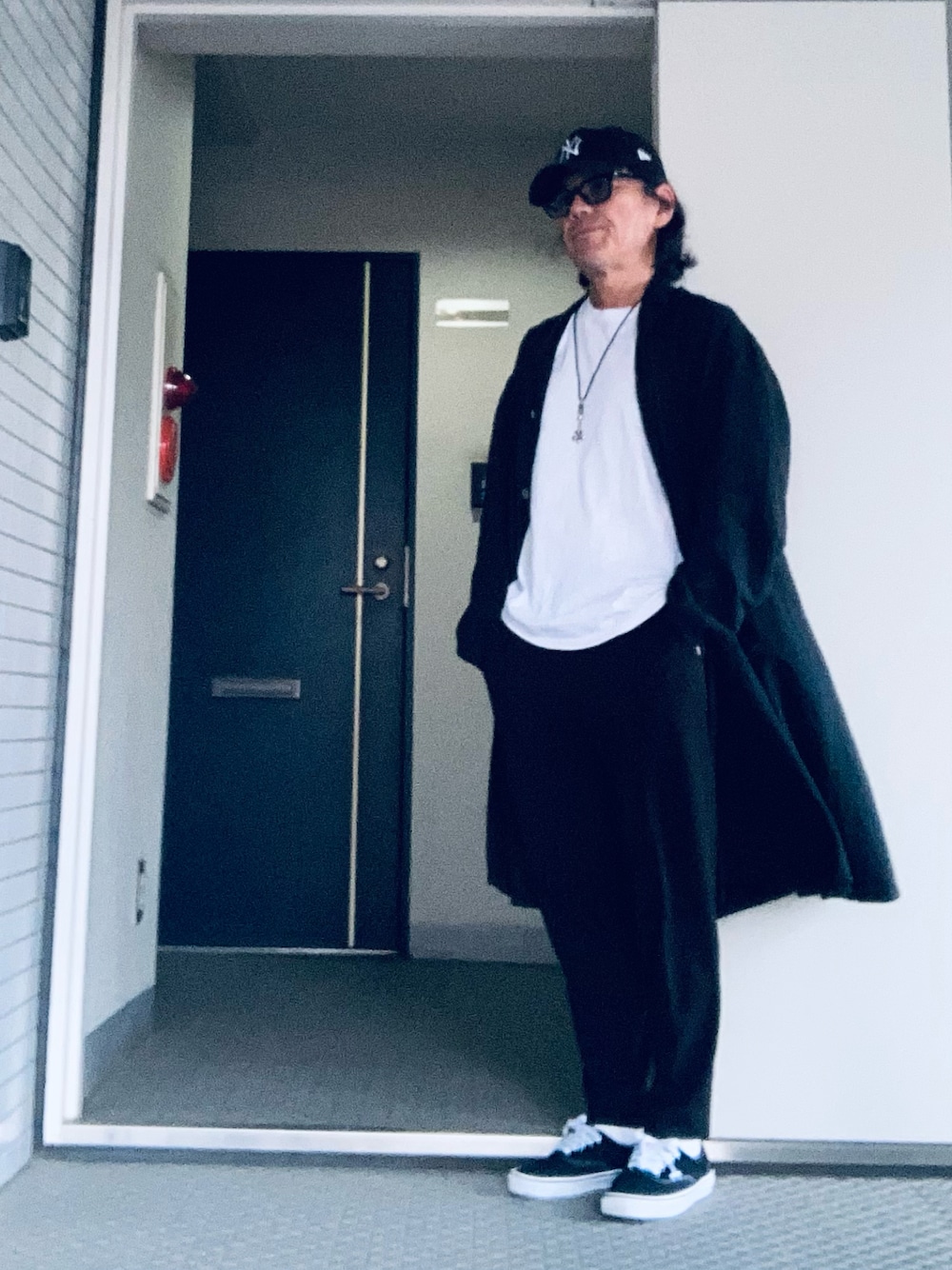 ホワイト系のTシャツ/カットソー、ブラック系のその他パンツ、ブラック系のステンカラーコートを着用したメンズの秋コーディネートの1枚目の写真