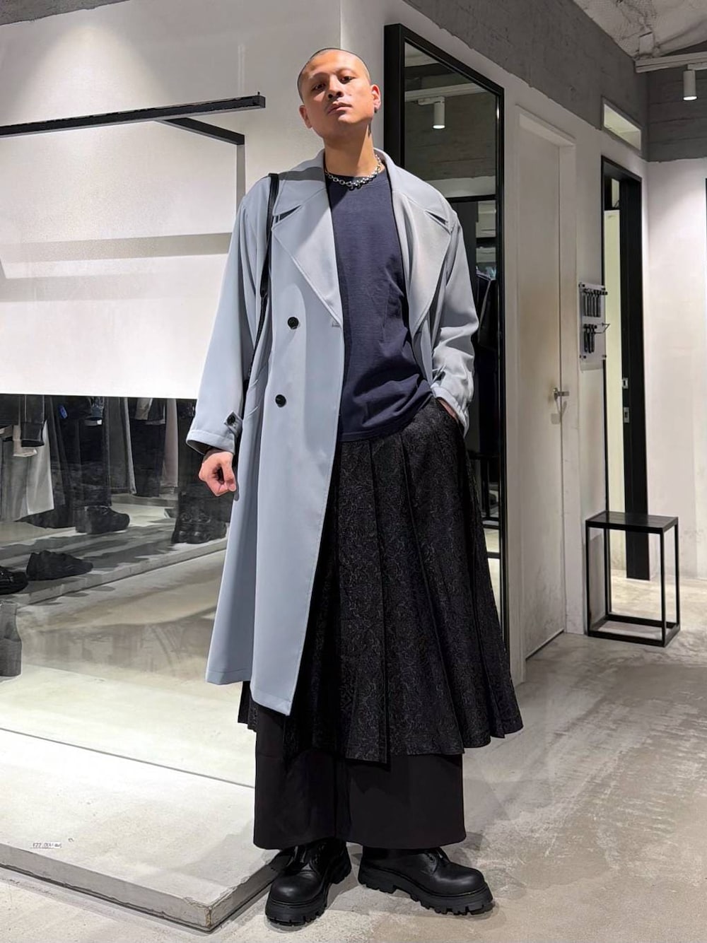 ブラック系のその他パンツ、ブラック系のドレスシューズ、グリーン系のトレンチコートを着用したメンズの春コーディネートの1枚目の写真