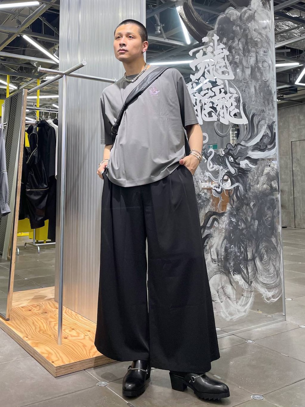 グレー系のTシャツ/カットソー、ブラック系のスラックス、ブラック系のショルダーバッグを着用したメンズの夏コーディネートの1枚目の写真