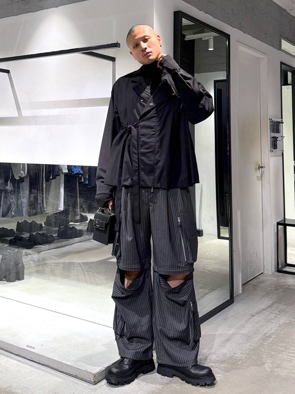 ブラック系のハンドバッグ、ブラック系のドレスシューズ、グレー系のカーゴパンツを着用したメンズの冬コーディネートの1枚目の写真