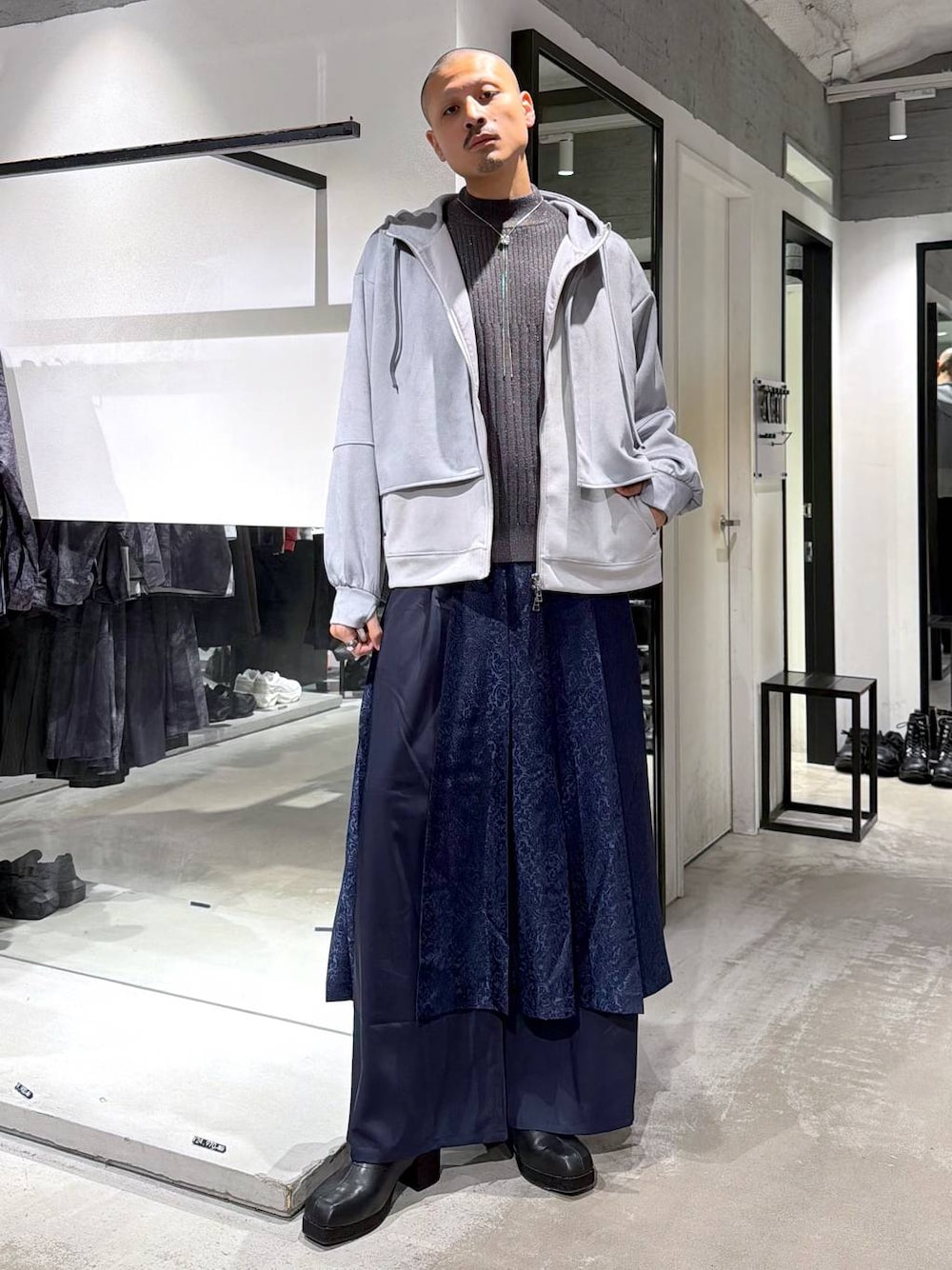 グレー系のニット/セーター、ブラック系のブーツ、ブルー系のその他パンツを着用したメンズの秋コーディネートの1枚目の写真