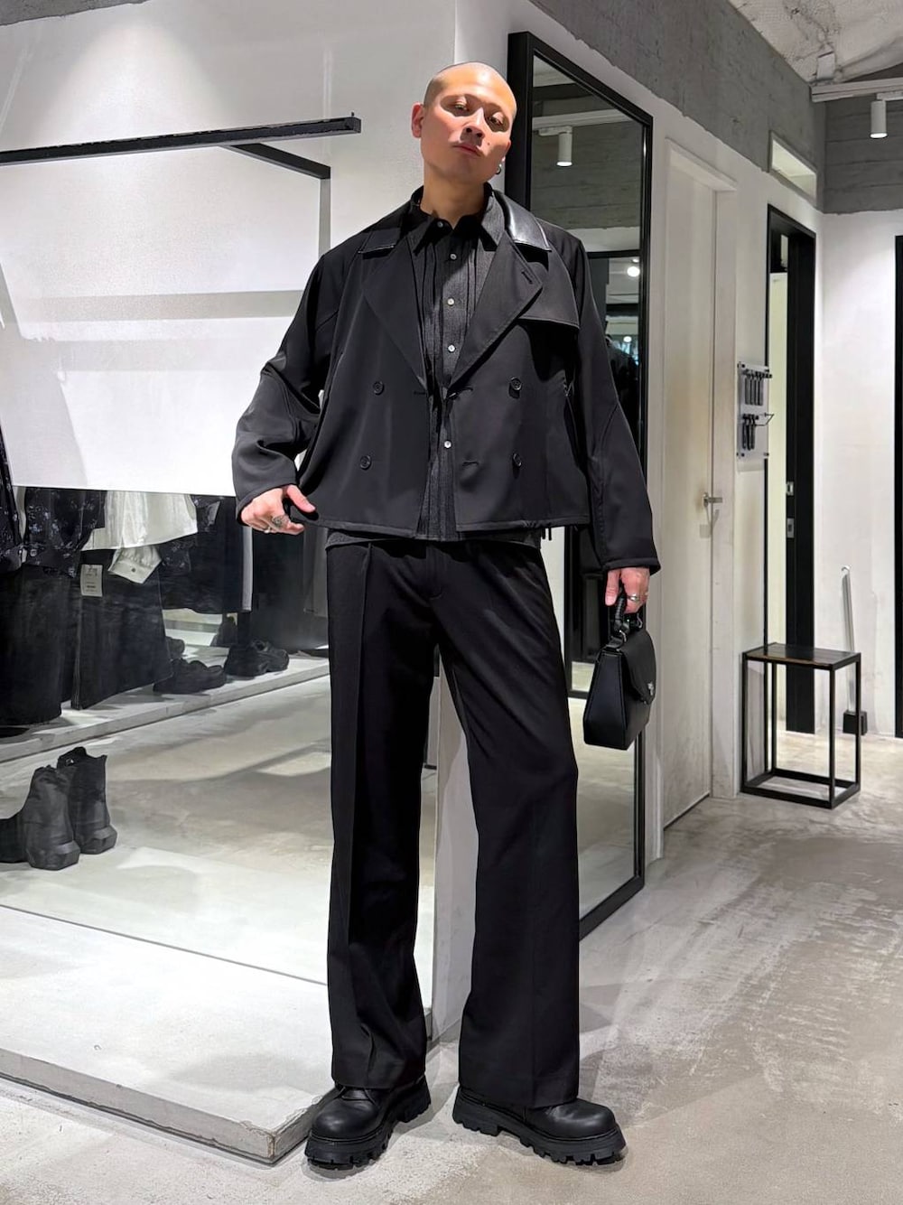 ブラック系のスラックス、ブラック系のハンドバッグ、ブラック系のドレスシューズを着用したメンズの春コーディネートの1枚目の写真