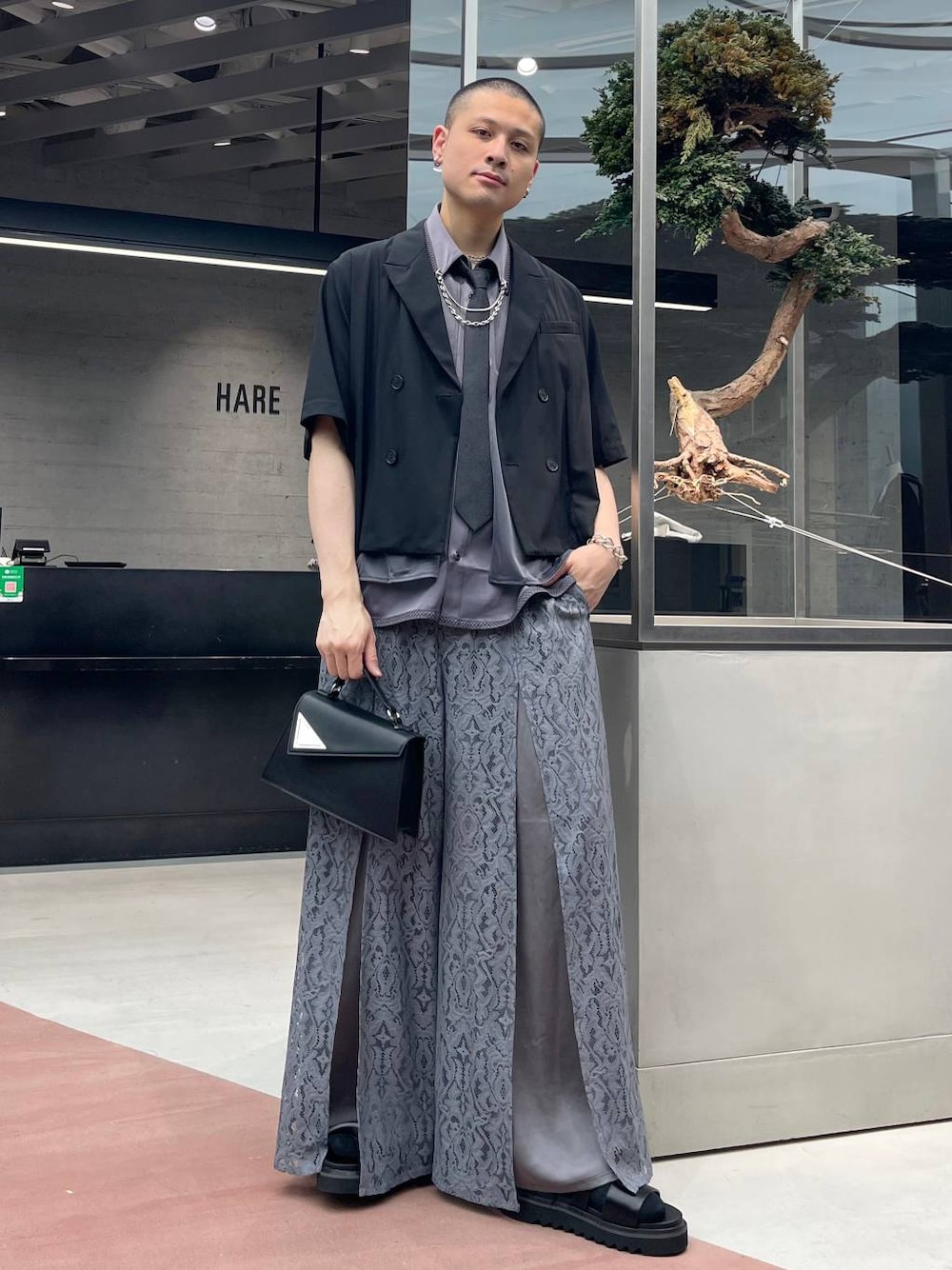 ブラック系のハンドバッグ、グレー系のその他パンツ、ブラック系のネクタイを着用したメンズの夏コーディネートの1枚目の写真