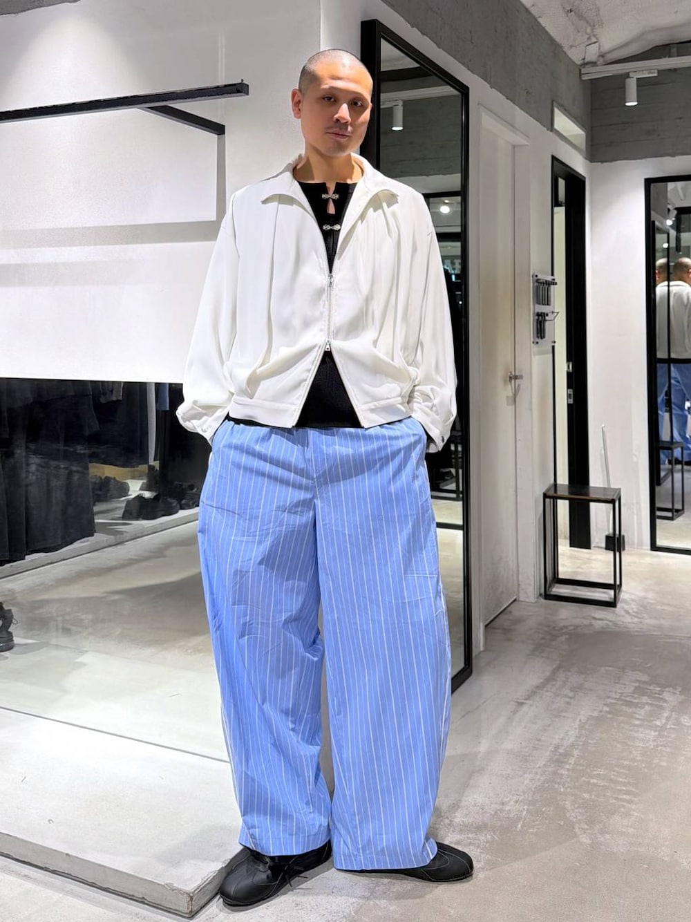 ホワイト系のブルゾン、ブルー系のスラックス、ブラック系のニット/セーターを着用したメンズの春コーディネートの1枚目の写真