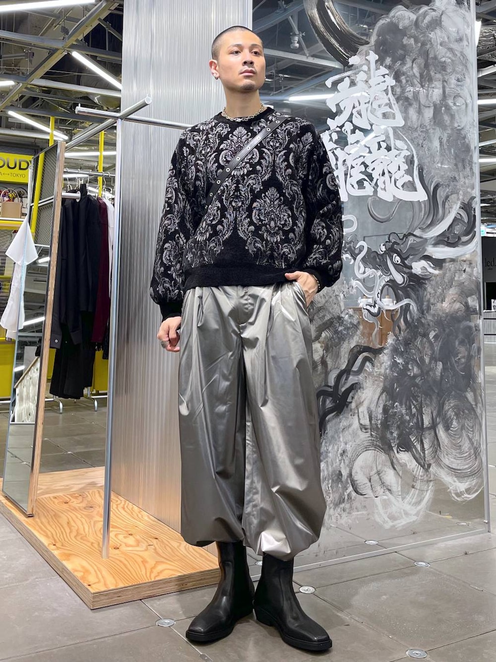 ブラック系のショルダーバッグ、ブラック系のニット/セーター、ブラック系のブーツを着用したメンズの秋コーディネートの1枚目の写真