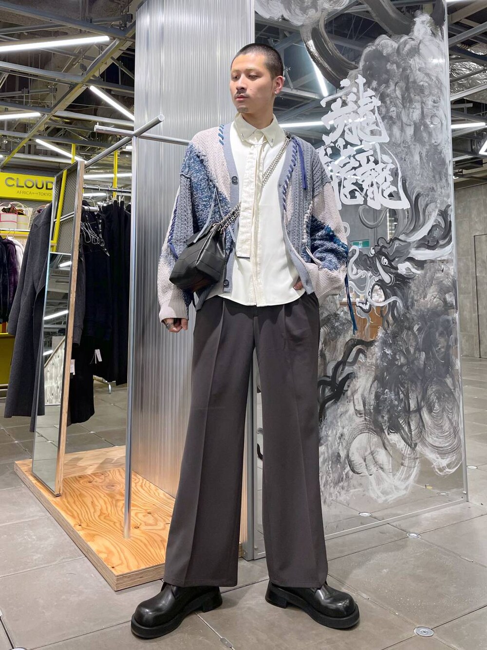 グレー系のカーディガン/ボレロ、ブラウン系のスラックス、ブラック系のショルダーバッグを着用したメンズの冬コーディネートの1枚目の写真