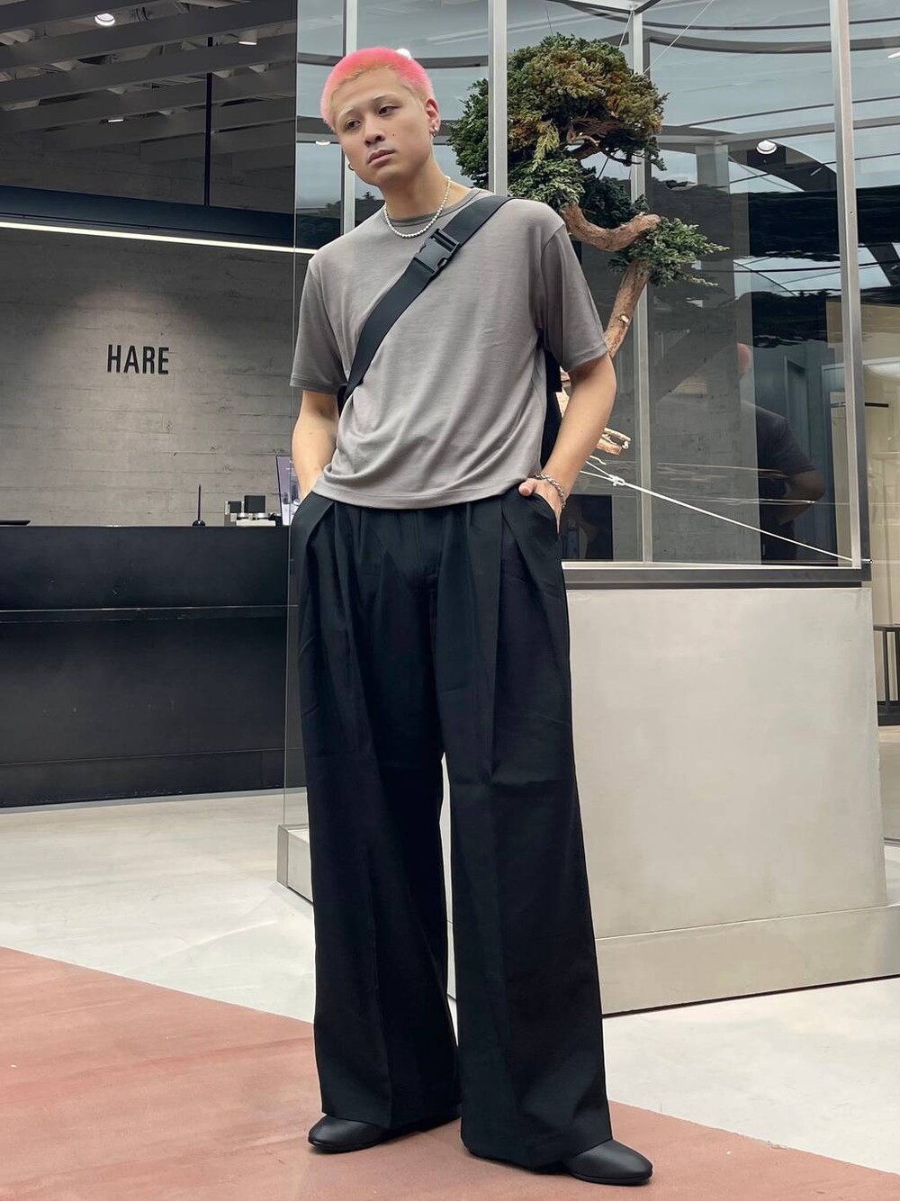 ブラック系のメッセンジャーバッグ、ベージュ系のTシャツ/カットソー、ブラック系のバレエシューズを着用したメンズの夏コーディネートの1枚目の写真