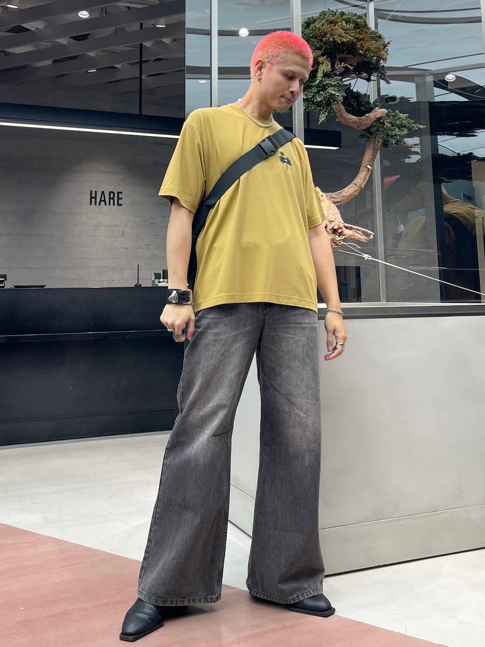 イエロー系のTシャツ/カットソー、ブラック系のメッセンジャーバッグ、ブラウン系のデニムパンツを着用したメンズの秋コーディネートの1枚目の写真