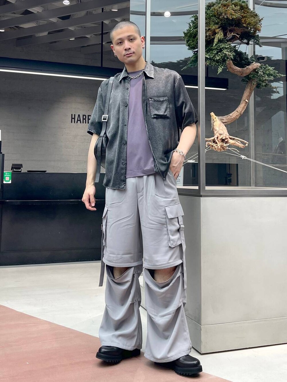 ブラック系のショルダーバッグ、グレー系のカーゴパンツ、パープル系のTシャツ/カットソーを着用したメンズの夏コーディネートの1枚目の写真