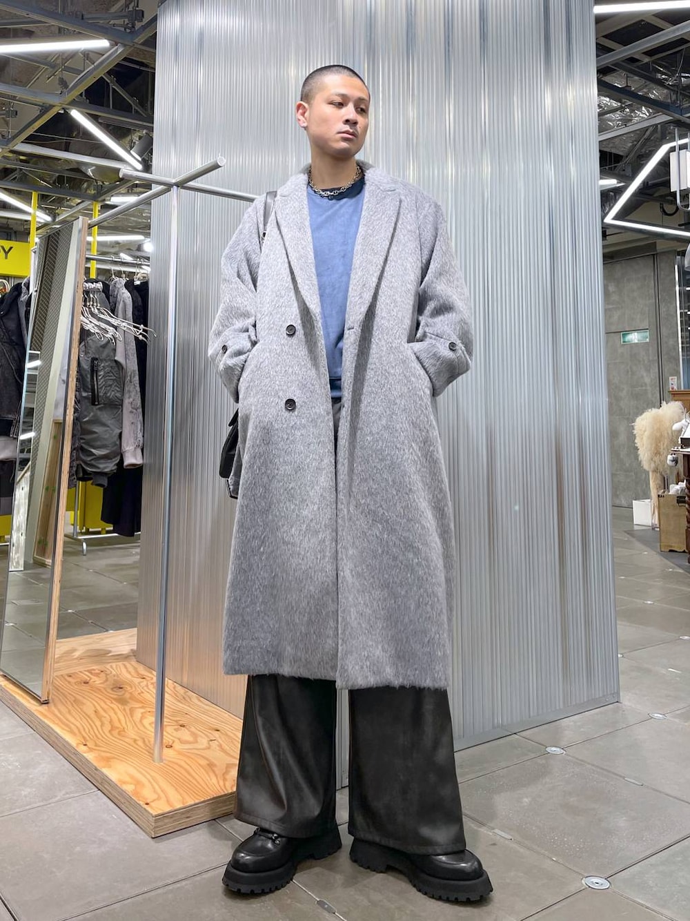 グレー系のトレンチコート、ブラック系のその他パンツ、ブルー系のスウェットを着用したメンズの冬コーディネートの1枚目の写真