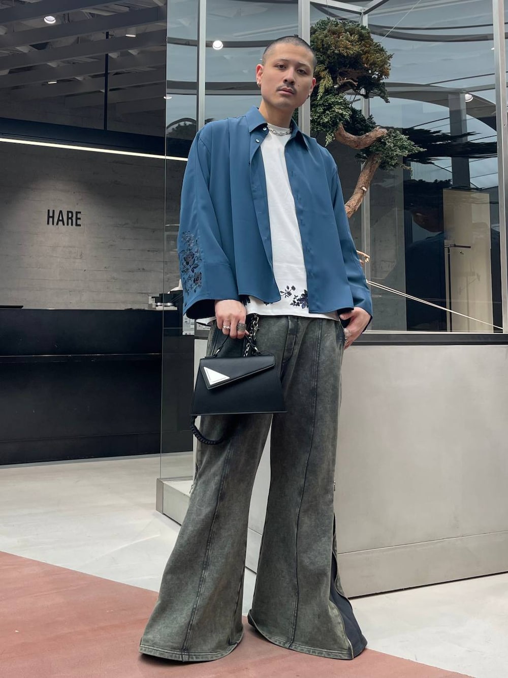 ブルー系のシャツ/ブラウス、ブラック系のハンドバッグ、ブラック系のスウェットパンツを着用したメンズの春コーディネートの1枚目の写真