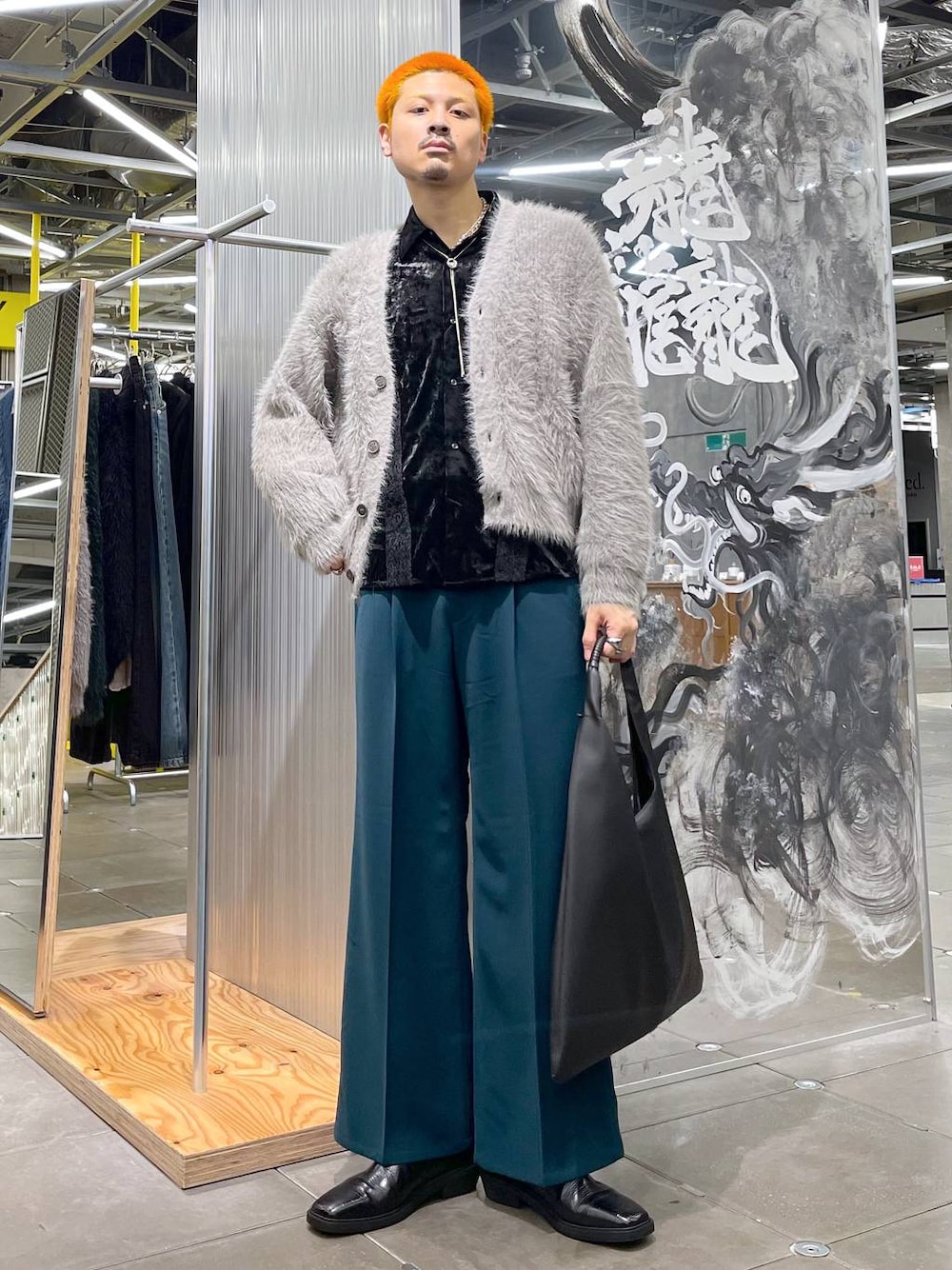 ブラック系のトートバッグ、グレー系のカーディガン/ボレロ、ブラック系のブーツを着用したメンズの秋コーディネートの1枚目の写真