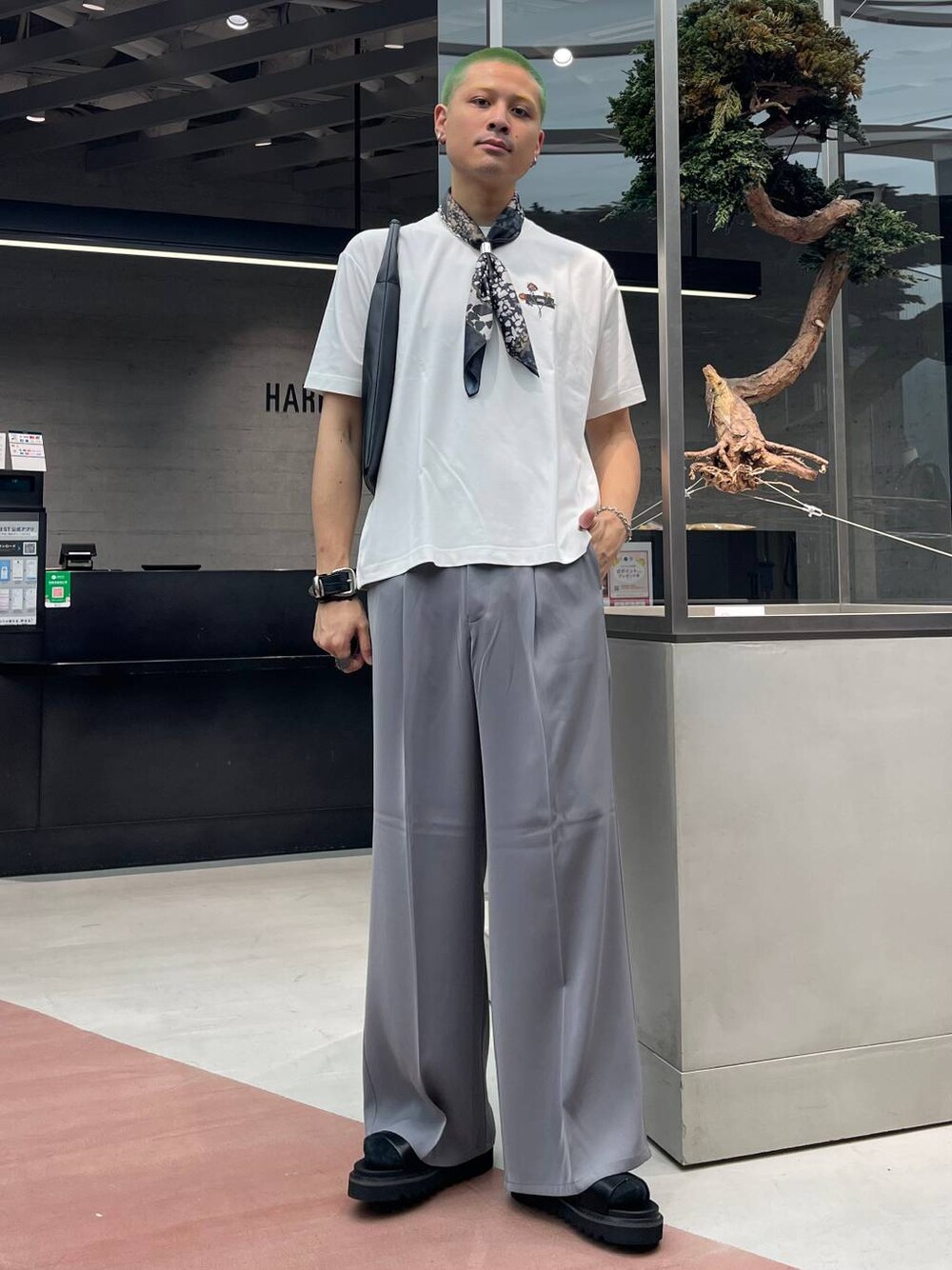 グレー系のスラックス、ブラック系のトートバッグ、ホワイト系のTシャツ/カットソーを着用したメンズの夏コーディネートの1枚目の写真