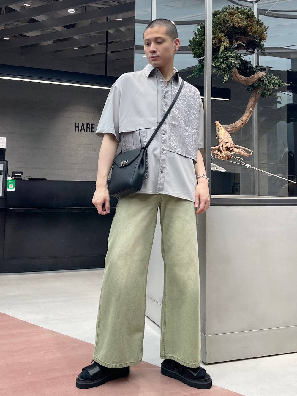 グリーン系のデニムパンツ、ブラック系のショルダーバッグ、ブラック系のサンダルを着用したメンズの夏コーディネートの1枚目の写真