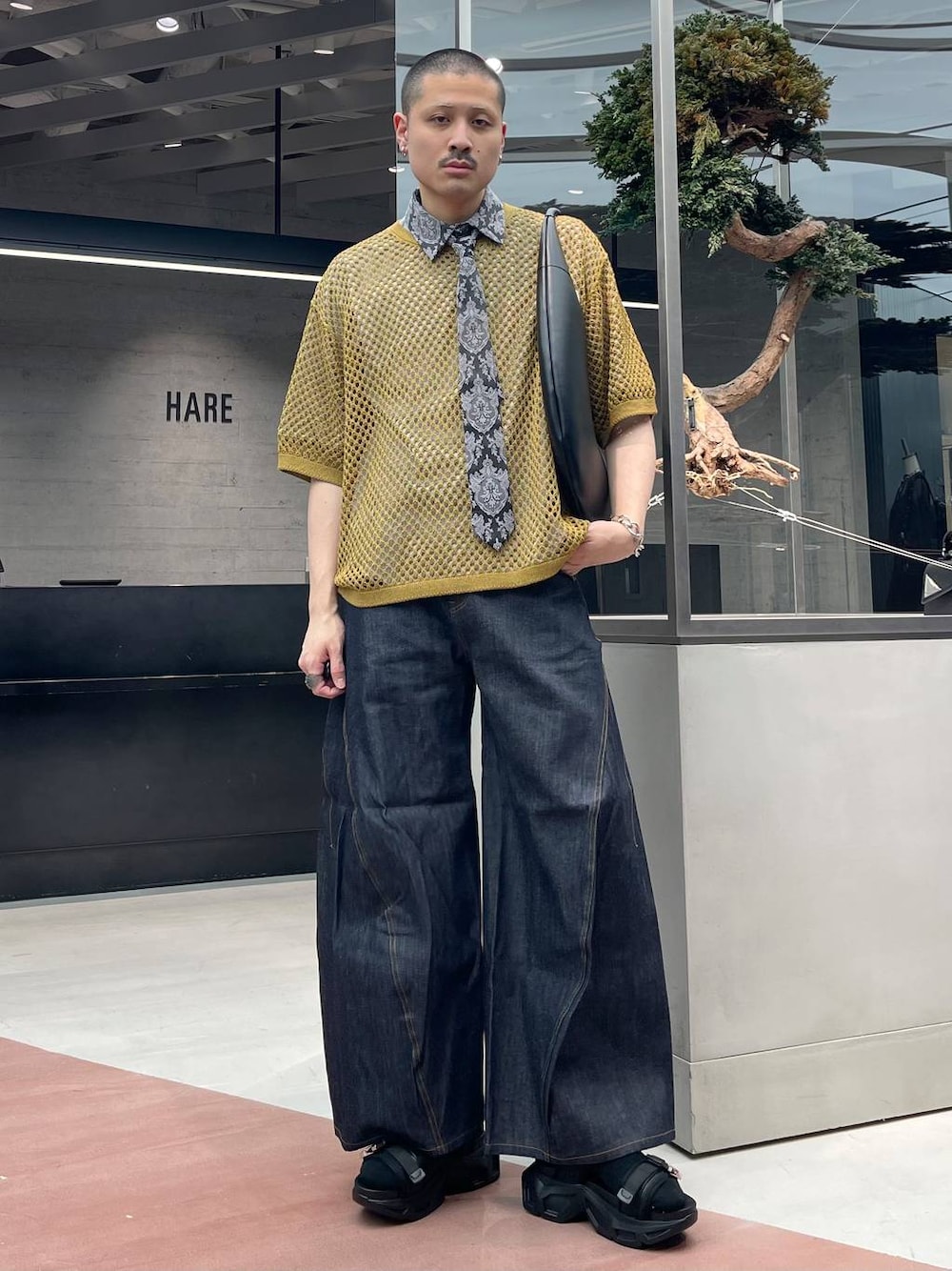 ブルー系のデニムパンツ、ブラック系のトートバッグ、ブラック系のサンダルを着用したメンズの春コーディネートの1枚目の写真