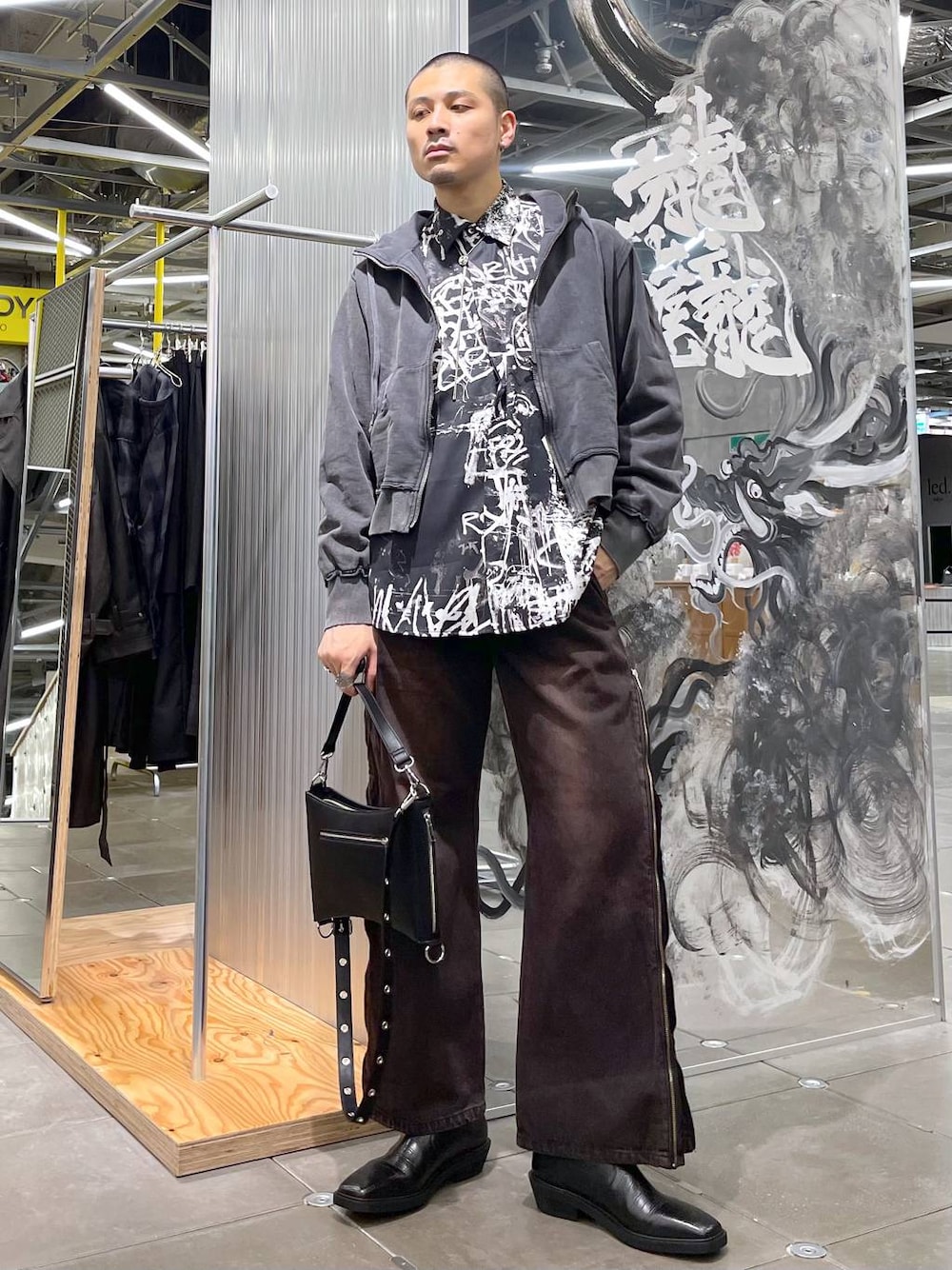 レッド系のデニムパンツ、グレー系のパーカー、ブラック系のショルダーバッグを着用したメンズの秋コーディネートの1枚目の写真