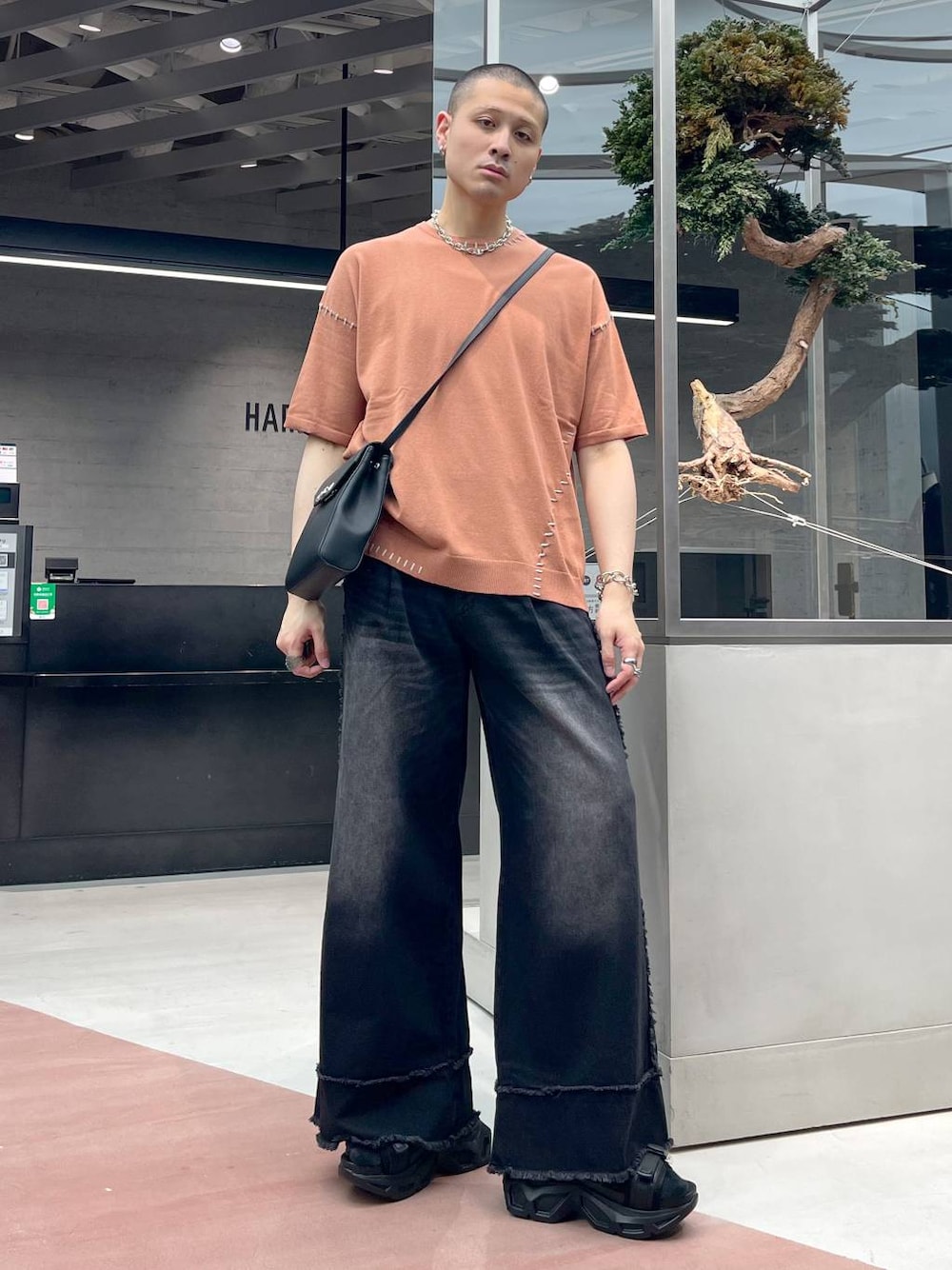 ブラック系のサンダル、ブラック系のデニムパンツ、オレンジ系のニット/セーターを着用したメンズの春コーディネートの1枚目の写真