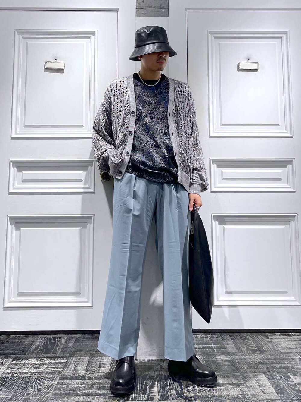 ブルー系のスラックス、ブラック系のドレスシューズ、ブラック系のトートバッグを着用したメンズの春コーディネートの1枚目の写真