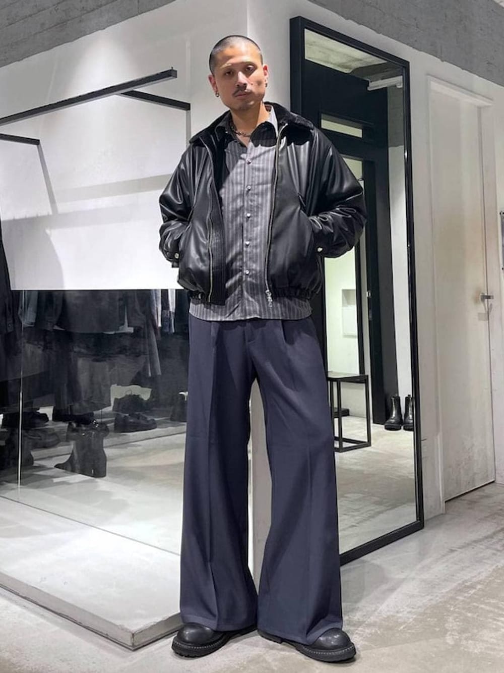 ブラック系のブルゾン、ブルー系のスラックス、ブラック系のショルダーバッグを着用したメンズの冬コーディネートの1枚目の写真