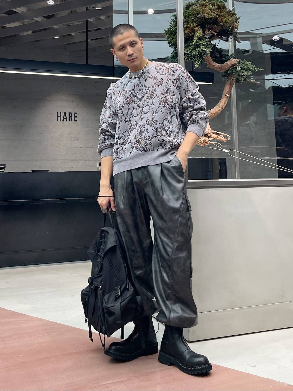 グレー系のニット/セーター、グレー系のカーゴパンツ、ブラック系のバックパック/リュックを着用したメンズの秋コーディネートの1枚目の写真