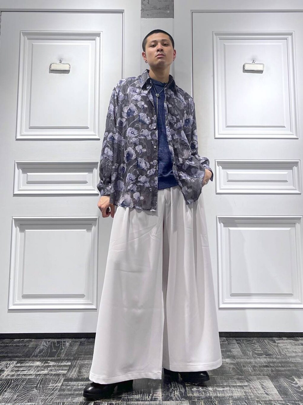 ブラック系のドレスシューズ、ブルー系のニット/セーター、ホワイト系のスラックスを着用したメンズの春コーディネートの1枚目の写真