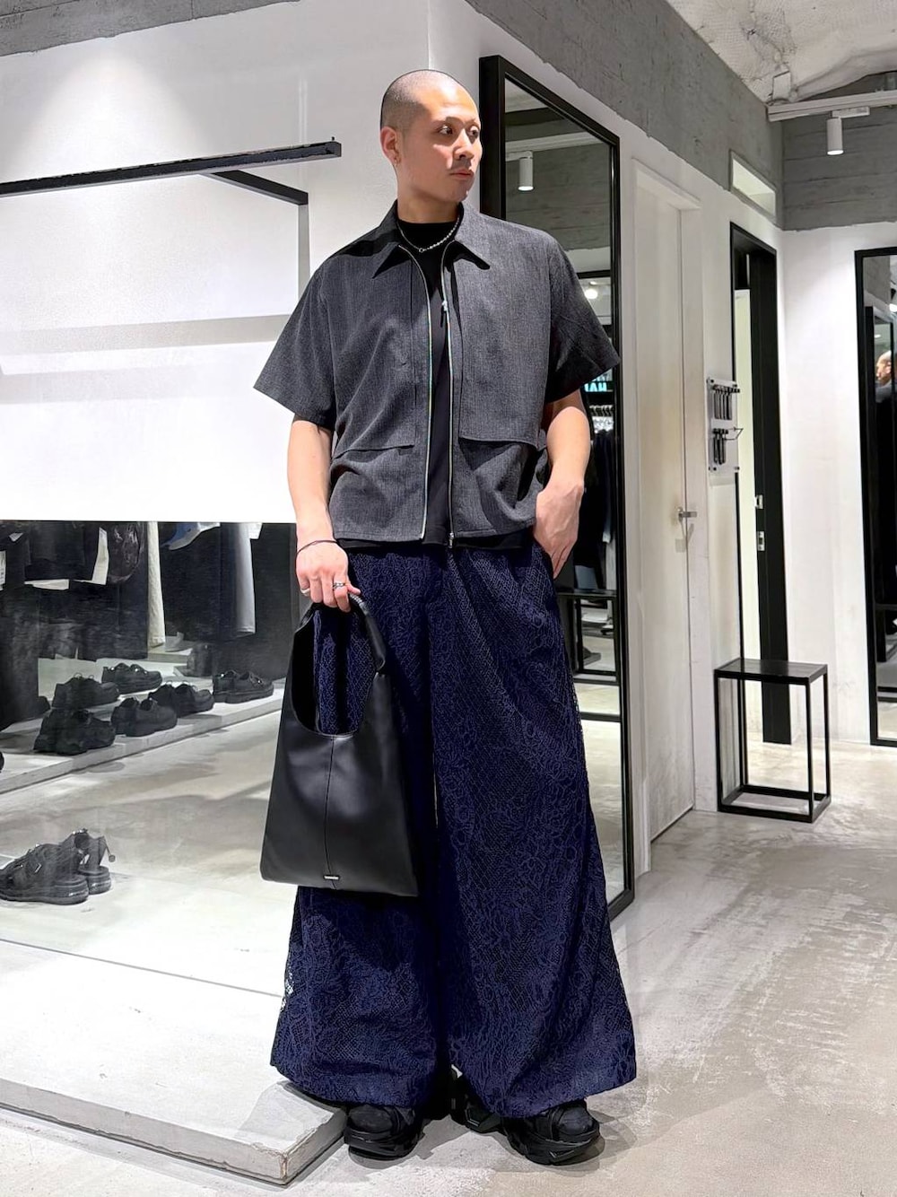 ブラック系のトートバッグ、ブラック系のサンダル、ブルー系のスラックスを着用したメンズの春コーディネートの1枚目の写真