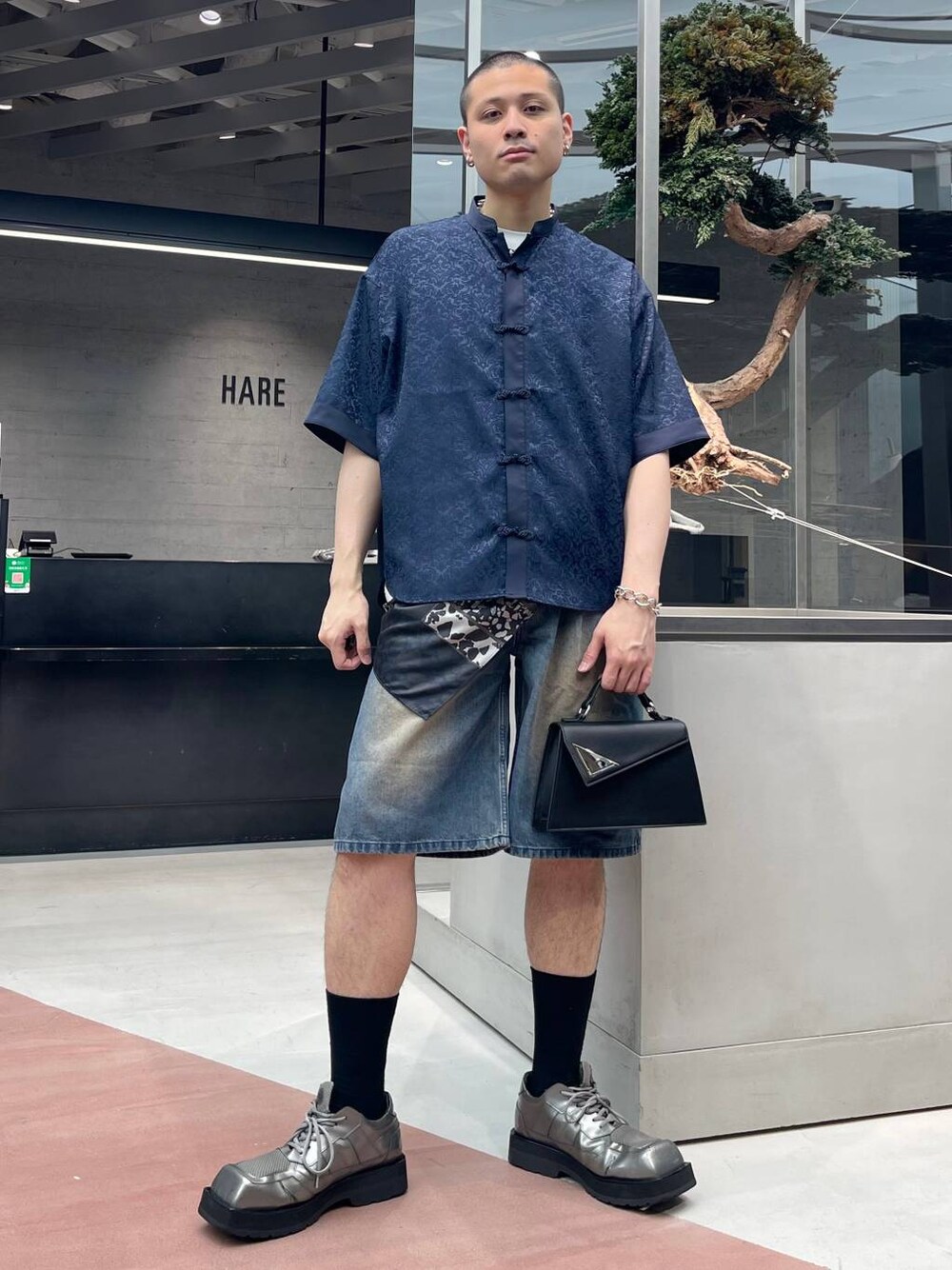 ブルー系のデニムパンツ、ブラック系のハンドバッグ、ブルー系のシャツ/ブラウスを着用したメンズの夏コーディネートの1枚目の写真