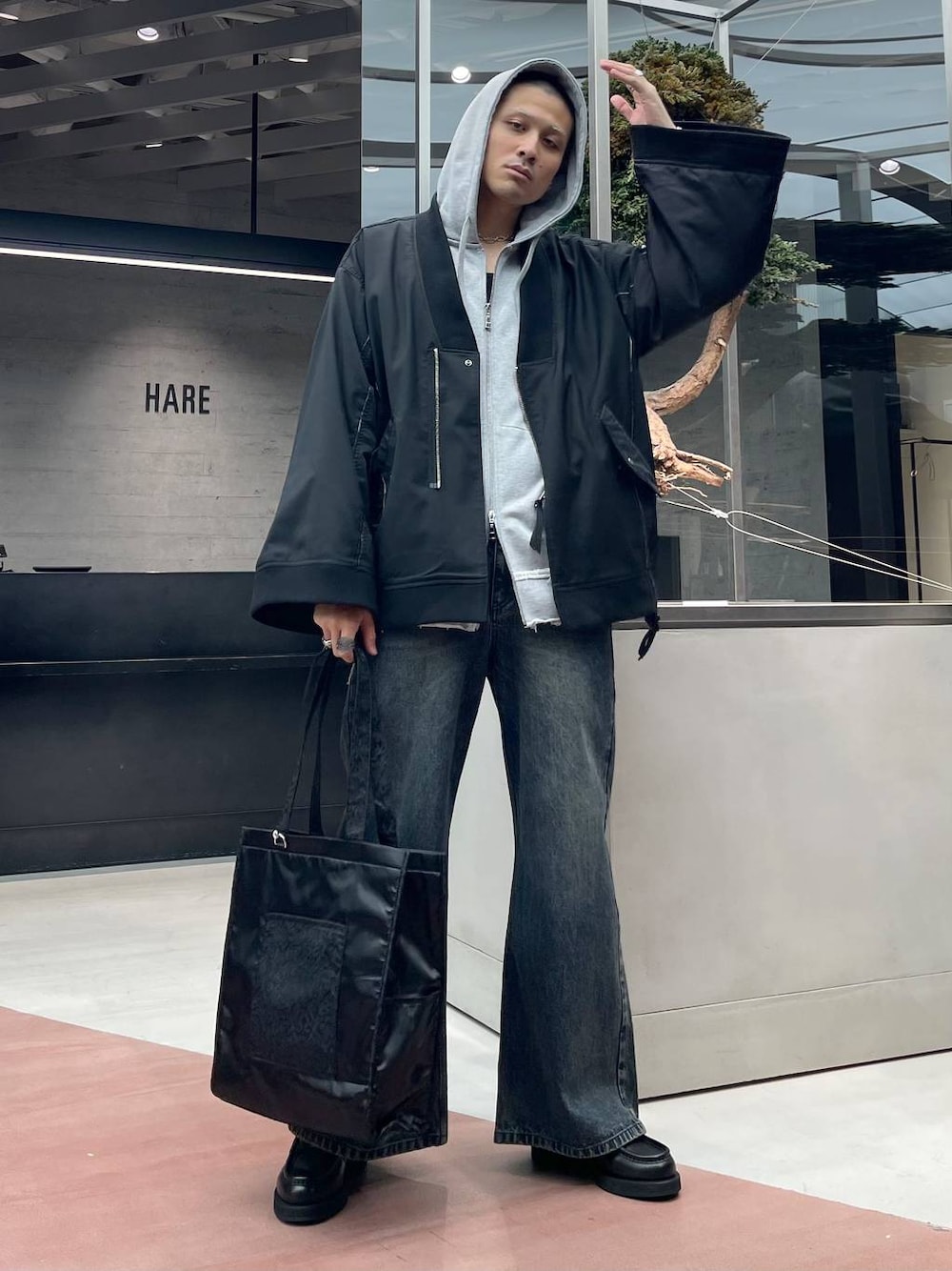 グレー系のパーカー、ブラック系のトートバッグ、ブラック系のローファーを着用したメンズの秋コーディネートの1枚目の写真