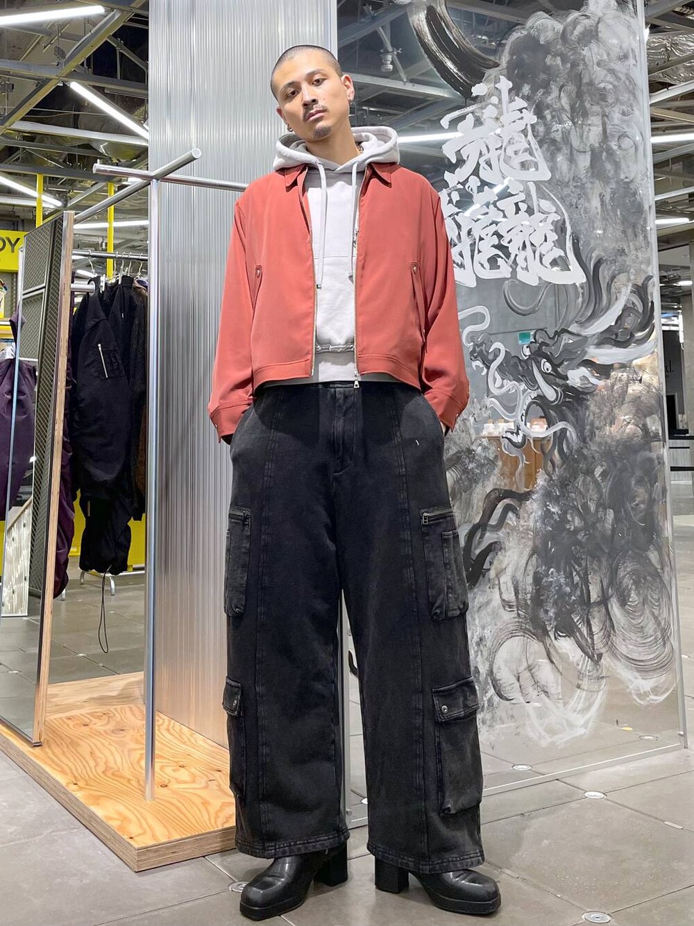 ブラック系のカーゴパンツ、オレンジ系のブルゾン、ブラック系のブーツを着用したメンズの秋コーディネートの1枚目の写真