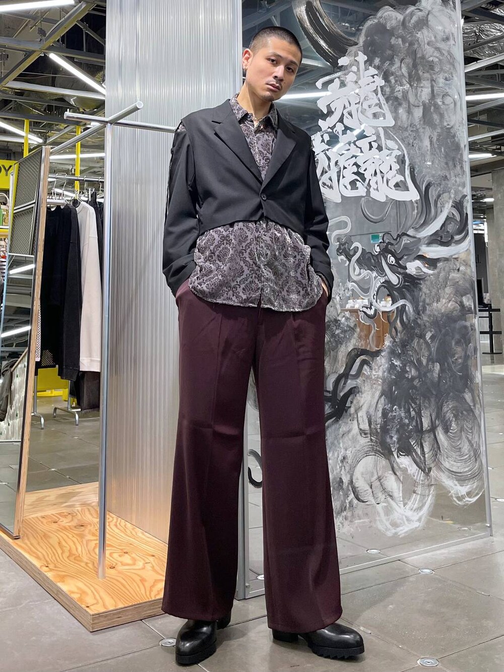 レッド系のスラックス、ブラック系のドレスシューズ、ブラック系のシャツ/ブラウスを着用したメンズの夏コーディネートの1枚目の写真