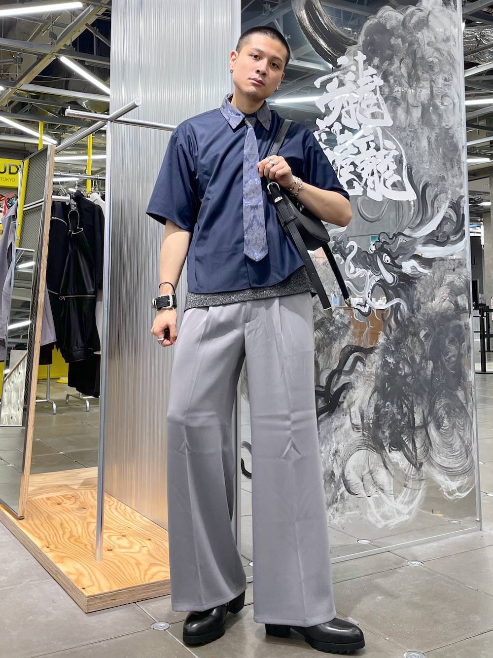 グレー系のスラックス、ブラック系のドレスシューズ、ブルー系のシャツ/ブラウスを着用したメンズの夏コーディネートの1枚目の写真