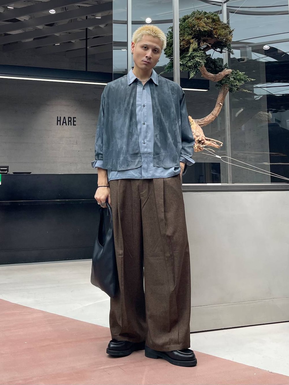 ブラック系のトートバッグ、ブラウン系のスラックス、ブラック系のローファーを着用したメンズの秋コーディネートの1枚目の写真