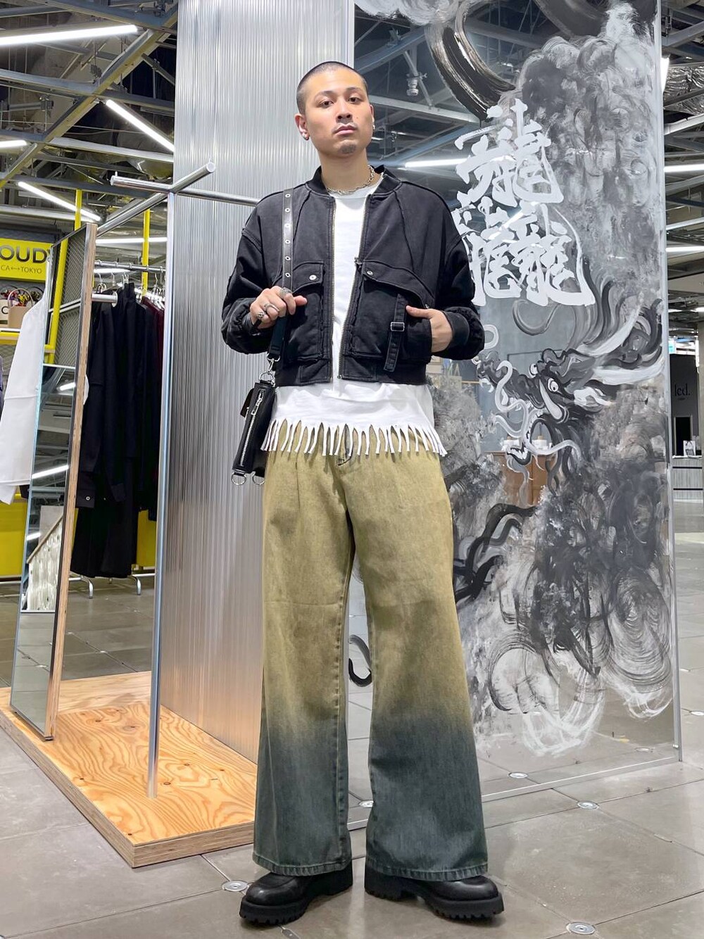 グリーン系のデニムパンツ、ブラック系のブルゾン、ブラック系のショルダーバッグを着用したメンズの秋コーディネートの1枚目の写真