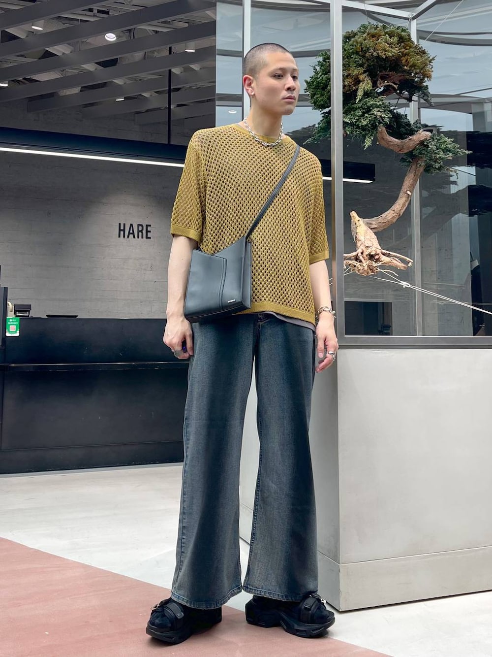 ブラック系のショルダーバッグ、ブラック系のサンダル、イエロー系のニット/セーターを着用したメンズの春コーディネートの1枚目の写真