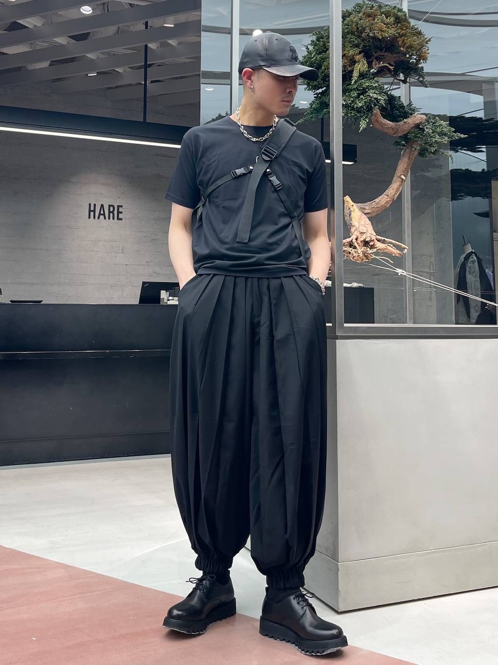 ブラック系のその他パンツ、ブラック系のショルダーバッグ、ブラック系のTシャツ/カットソーを着用したメンズの春コーディネートの1枚目の写真