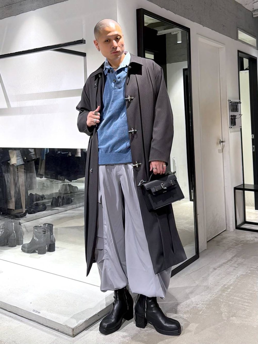 ブルー系のポロシャツ、ブラック系のブーツ、ブラック系のハンドバッグを着用したメンズの冬コーディネートの1枚目の写真