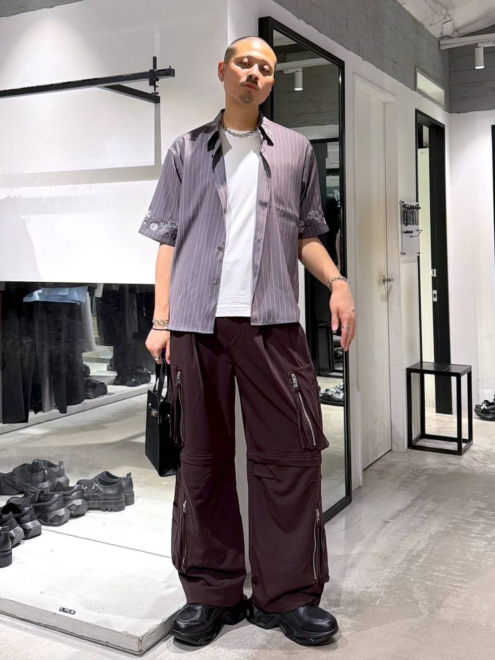 ブラック系のスニーカー、ホワイト系のTシャツ/カットソー、ブラウン系のカーゴパンツを着用したメンズの夏コーディネートの1枚目の写真