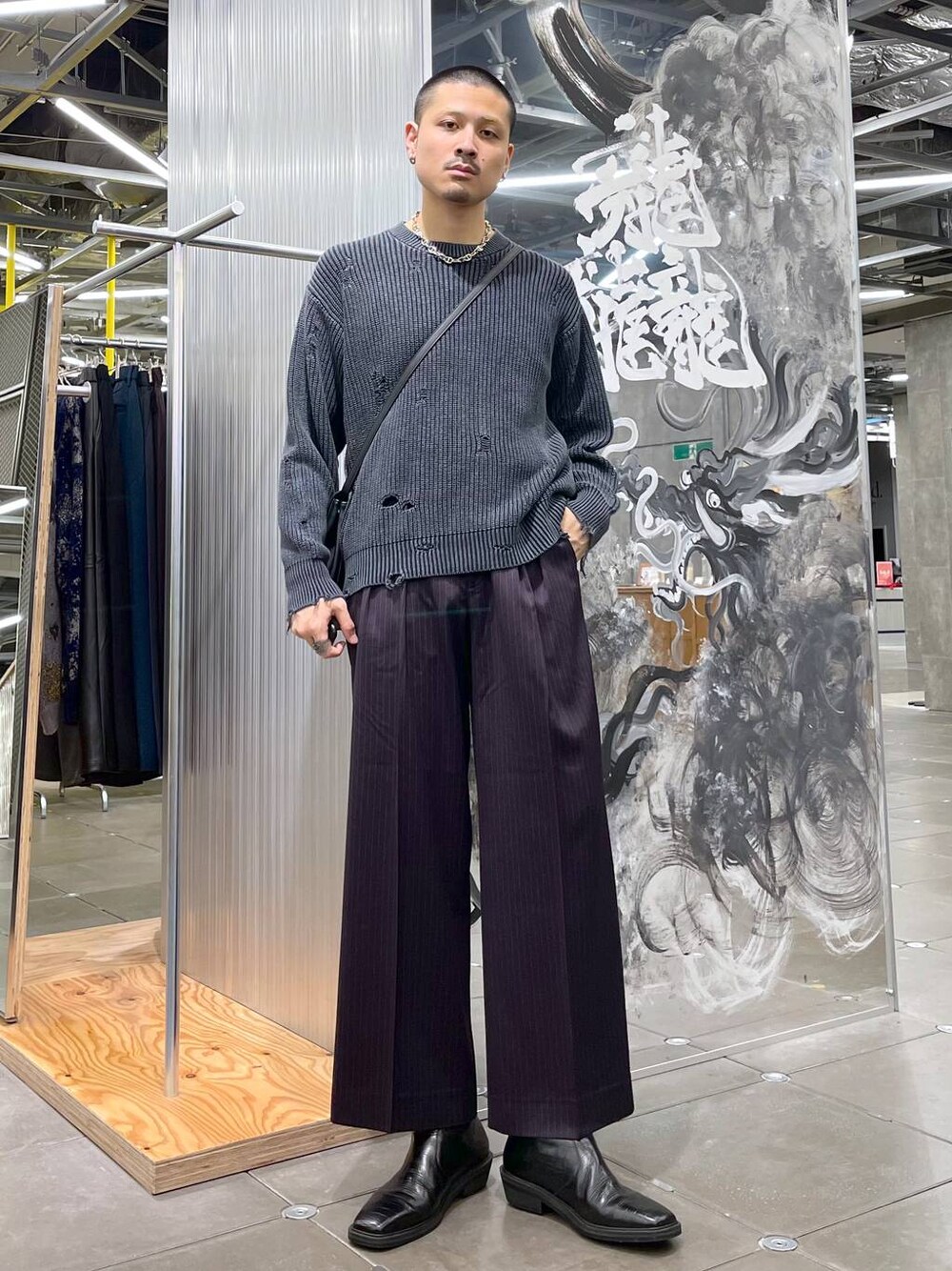 ブラック系のブーツ、パープル系のスラックス、ブラック系のショルダーバッグを着用したメンズの冬コーディネートの1枚目の写真