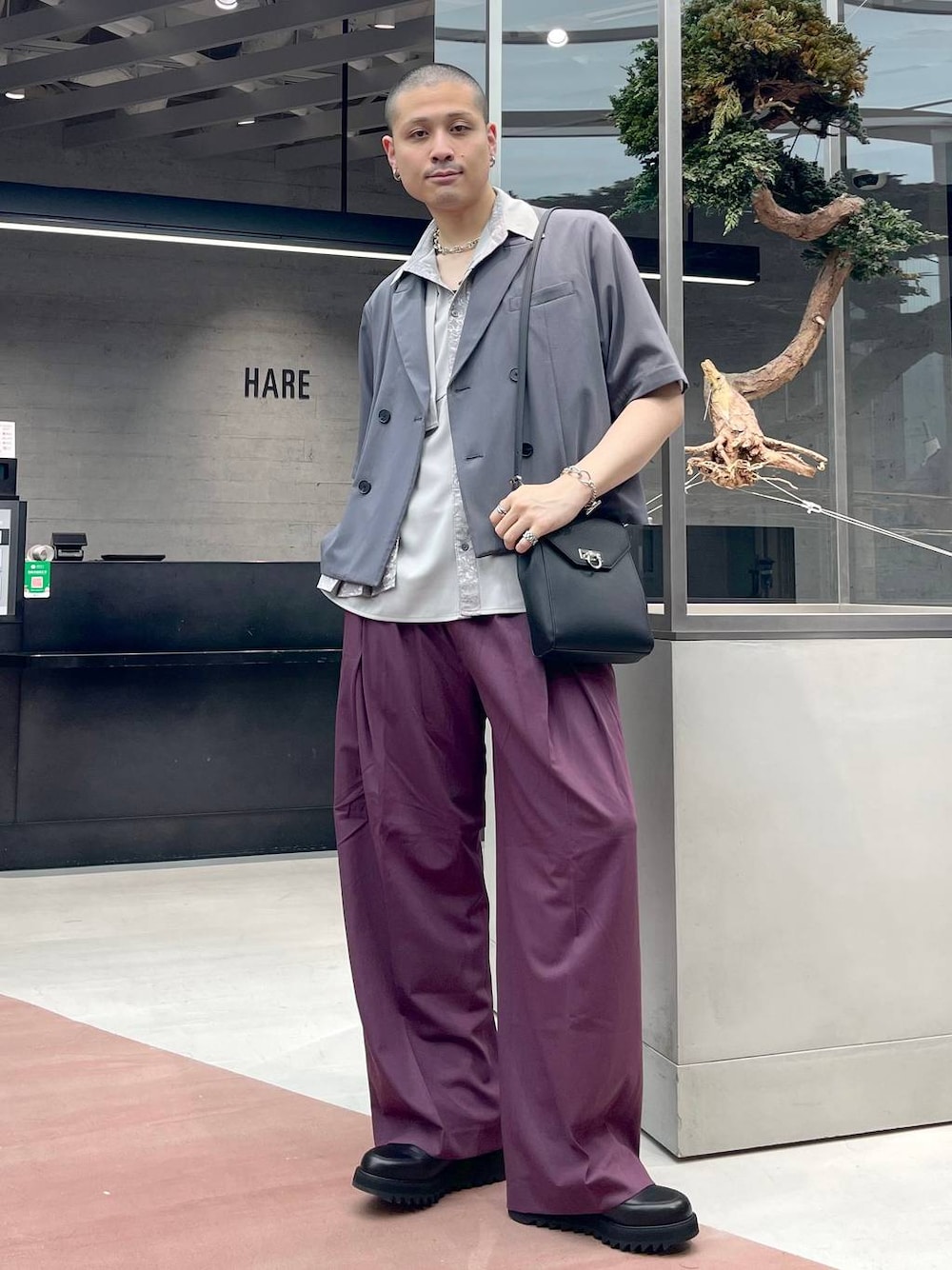 ブラック系のショルダーバッグ、レッド系のスラックス、グレー系のテーラードジャケットを着用したメンズの夏コーディネートの1枚目の写真